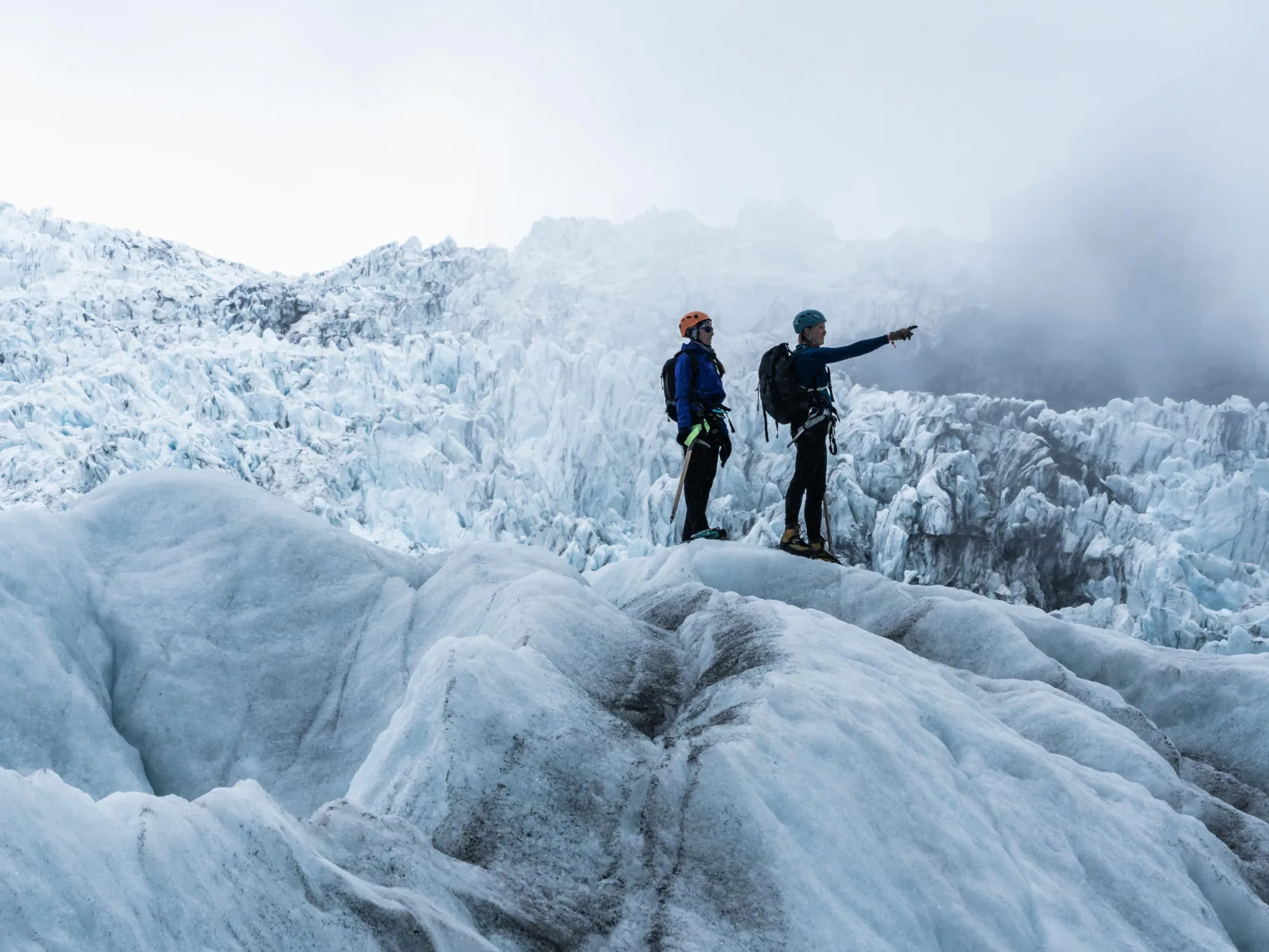 Zwei Personen stehen in nebligem Wetter auf einem Gletscher in Island und schauen sich um