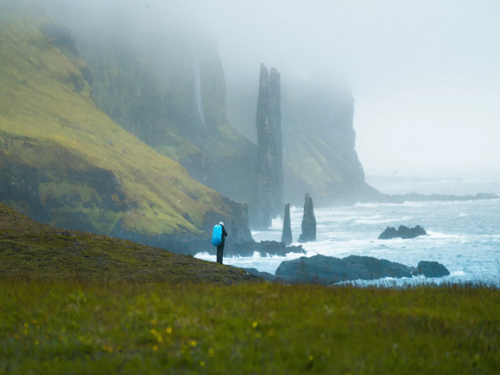Wanderer der im Nebel steht und das unruhige Meer beobachtet im Gebiet Hornstrandir in den Westfjorden Islands