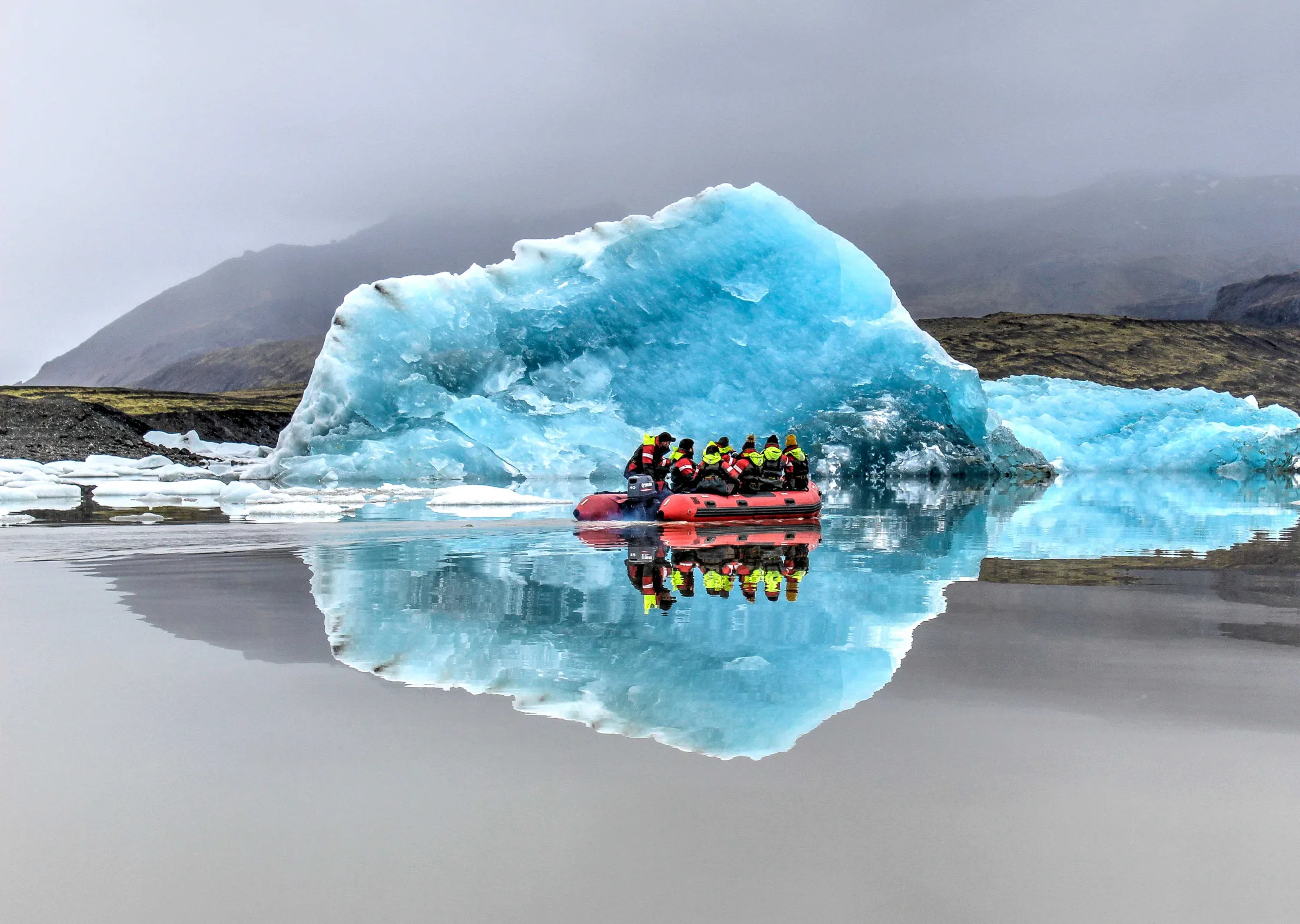 Bootsgruppe, die einen Eisberg betrachtet, im Gletschersee Fjallsárlón in Südisland