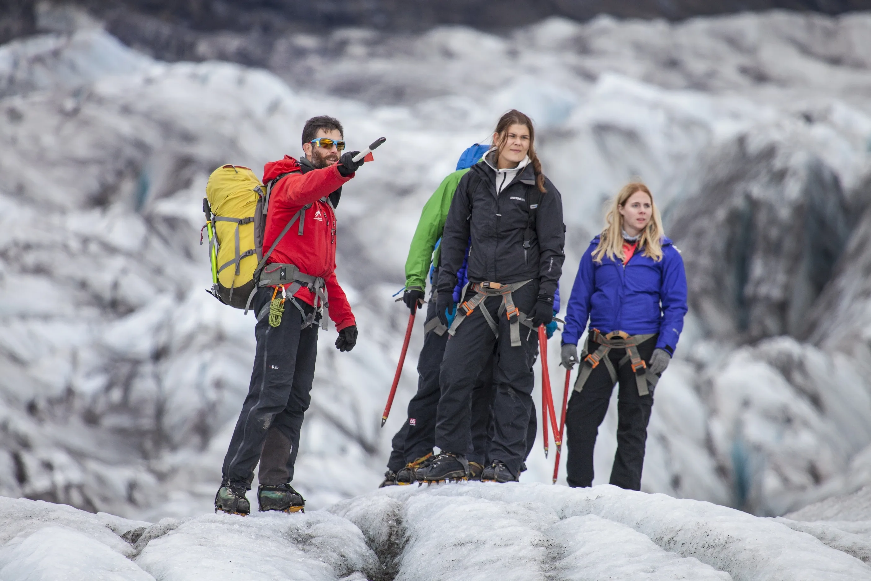 Guide zeigt der Reisegruppe etwas in der Ferne bei einer Gletscherwanderung auf dem isländischen Gletscher Svinafellsjökull