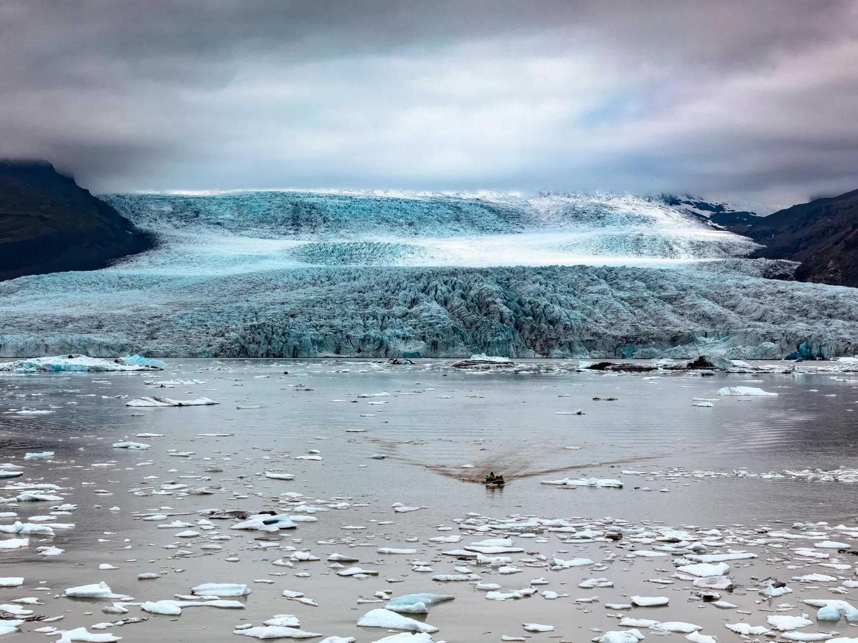 Fjallsárlón Gletscherlagune, Foto: Heinz Landsberg
Ausflugsboot fahrt auf der Lagune, im Hintergrund der Gletscher, mit Wolken verhangener Himmel