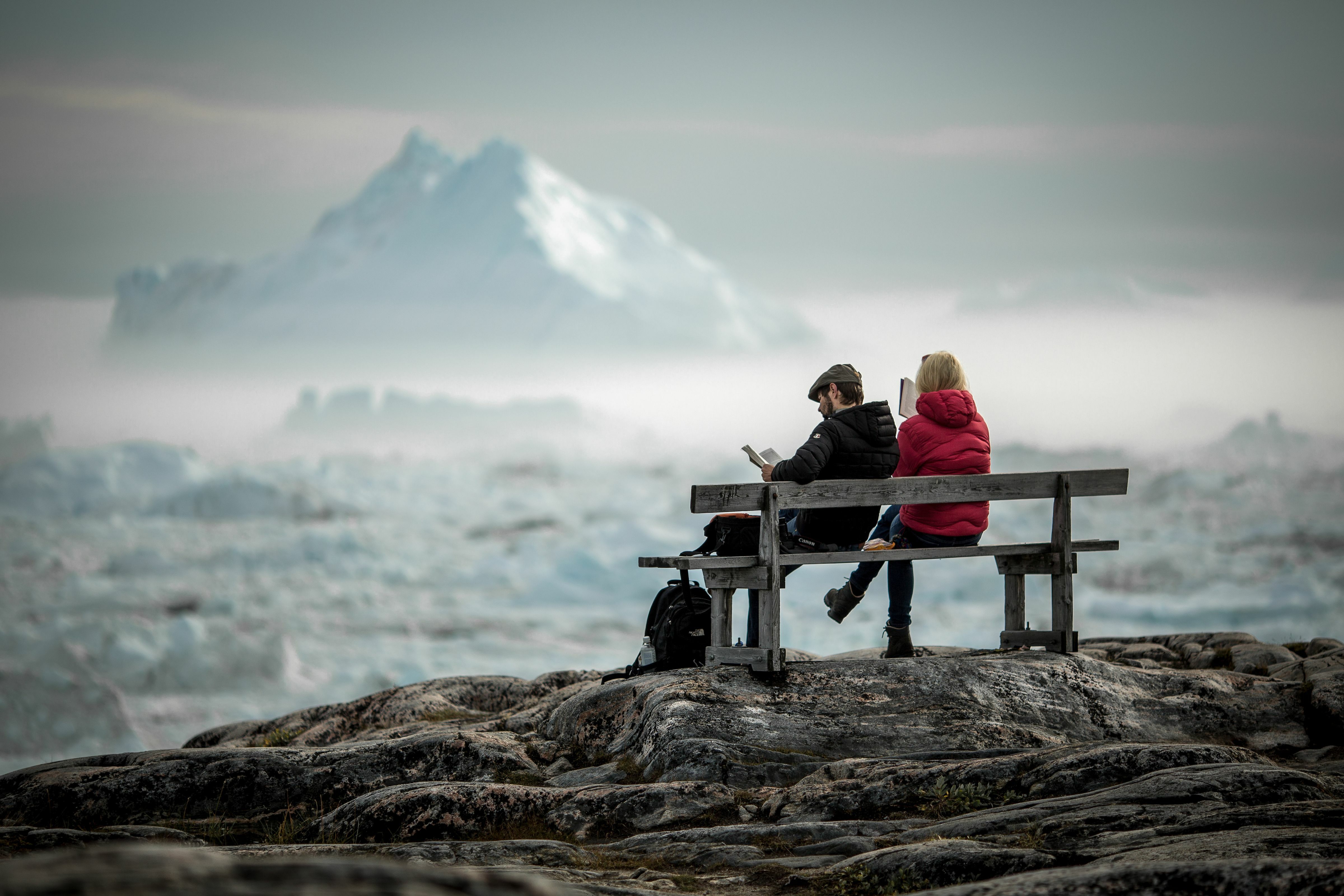 Nordgrönland: Reisende auf einer Bank schauen auf Eisberge im Eisfjord