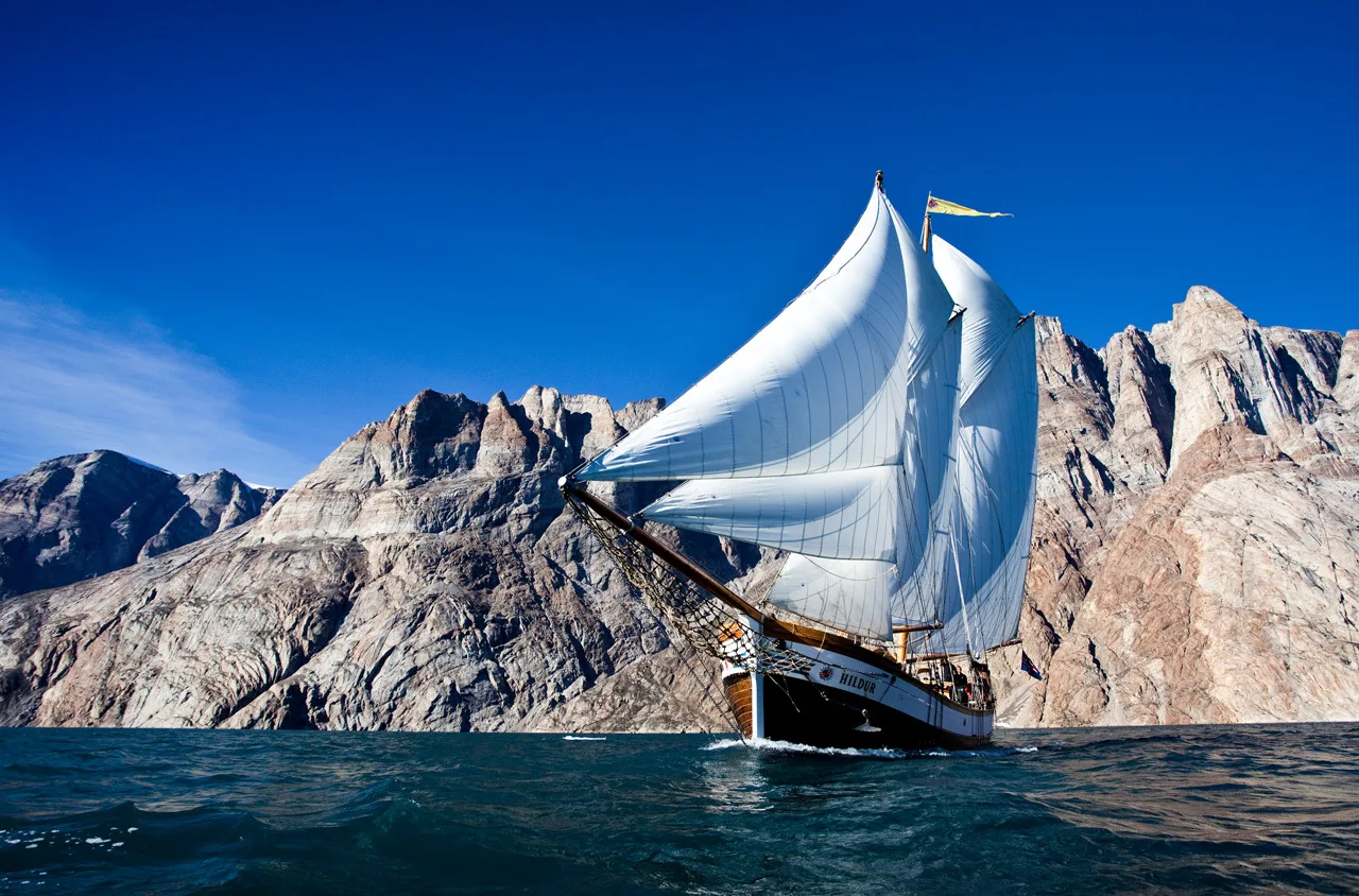 Segeltour in Grönland; großes Segelschiff vor kargen Bergen