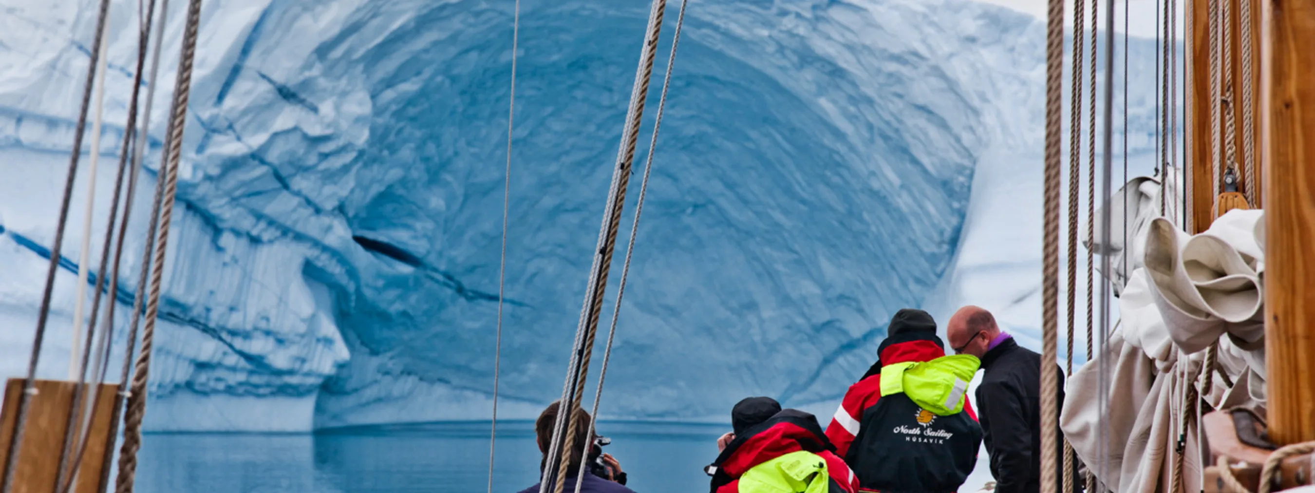 Teilnehmer der Segeltour bestaunen einen riesigen Eisberg