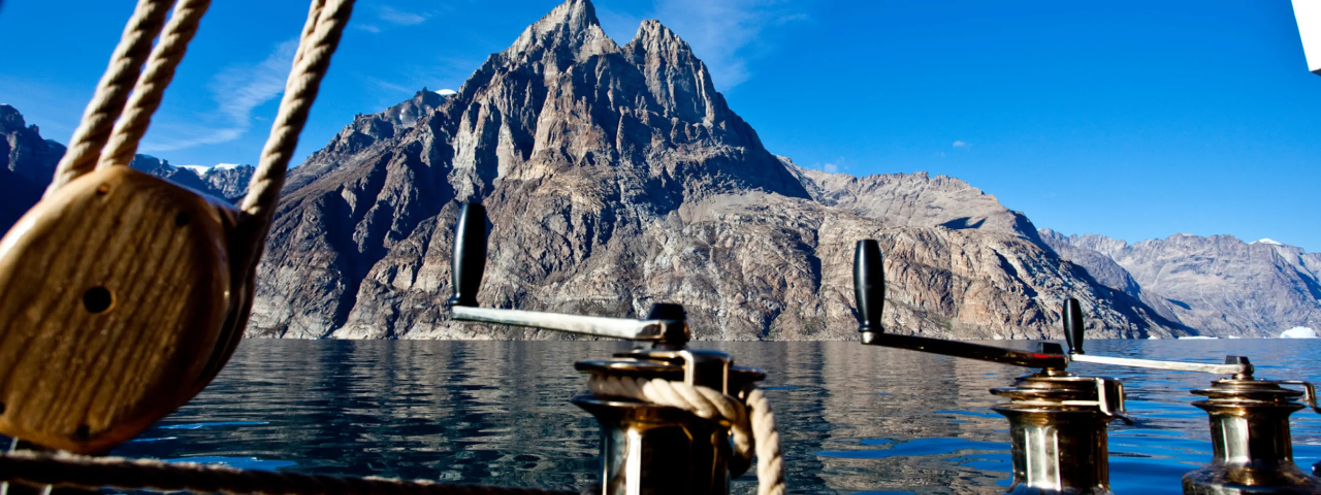 Traditionelle Segeltour in Scorebysund, Ostgrönland
Blick vom Segelboot auf einen Fjord und schroffe Bergspitzen