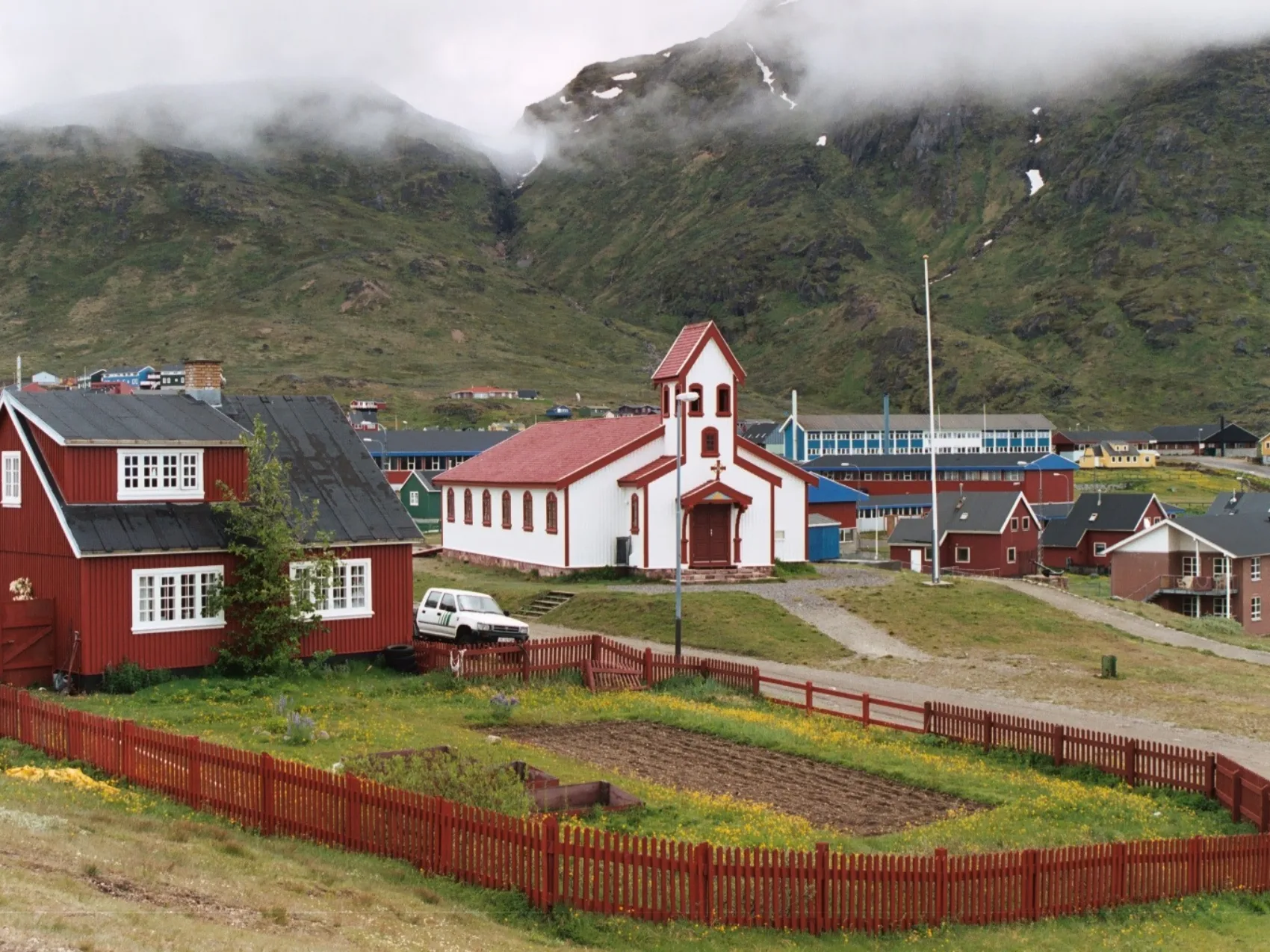 Siedlung Narsaq in Südgrönland, Häuser und Kirche vor Bergen mit Nebel