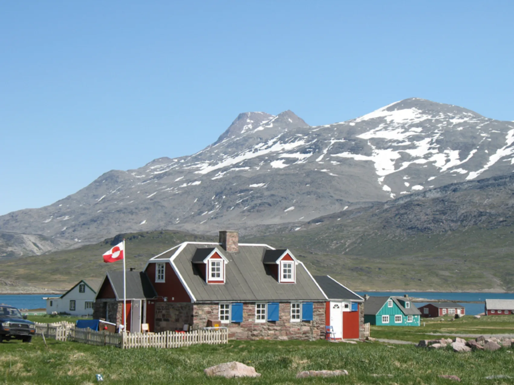 Südgrönland: Siedlung Igaliku
Steinhaus mit Fahne im Garten
Im Hintergrund leicht mit Schnee bedeckte Berge