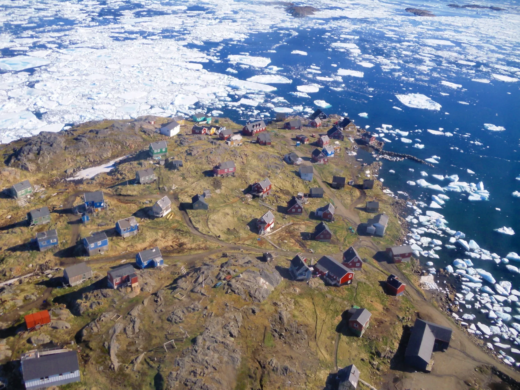 Ostgrönland Kulusuk Eisberge im Meer und Häuser auf der felsigen Spitze, verteilt