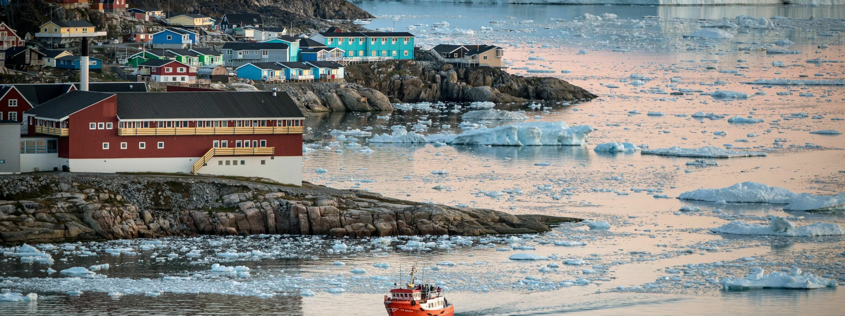 Nordgrönland: Hafen Ilulissat; 
kleines Schiff fährt im Hafen ein, im Hintergrund Eisberge
