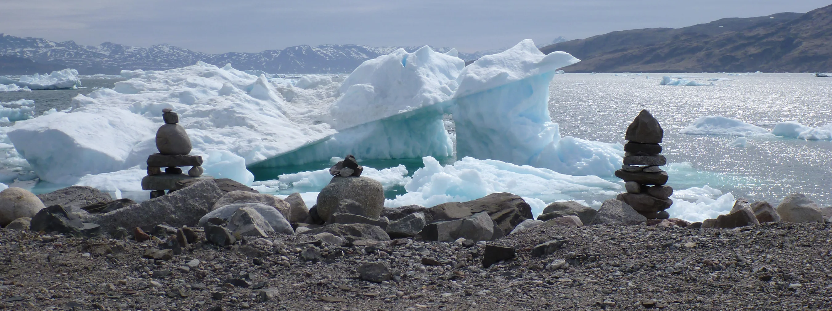 kleine Steintürme vor Eisbergen und Berge im Hintergrund