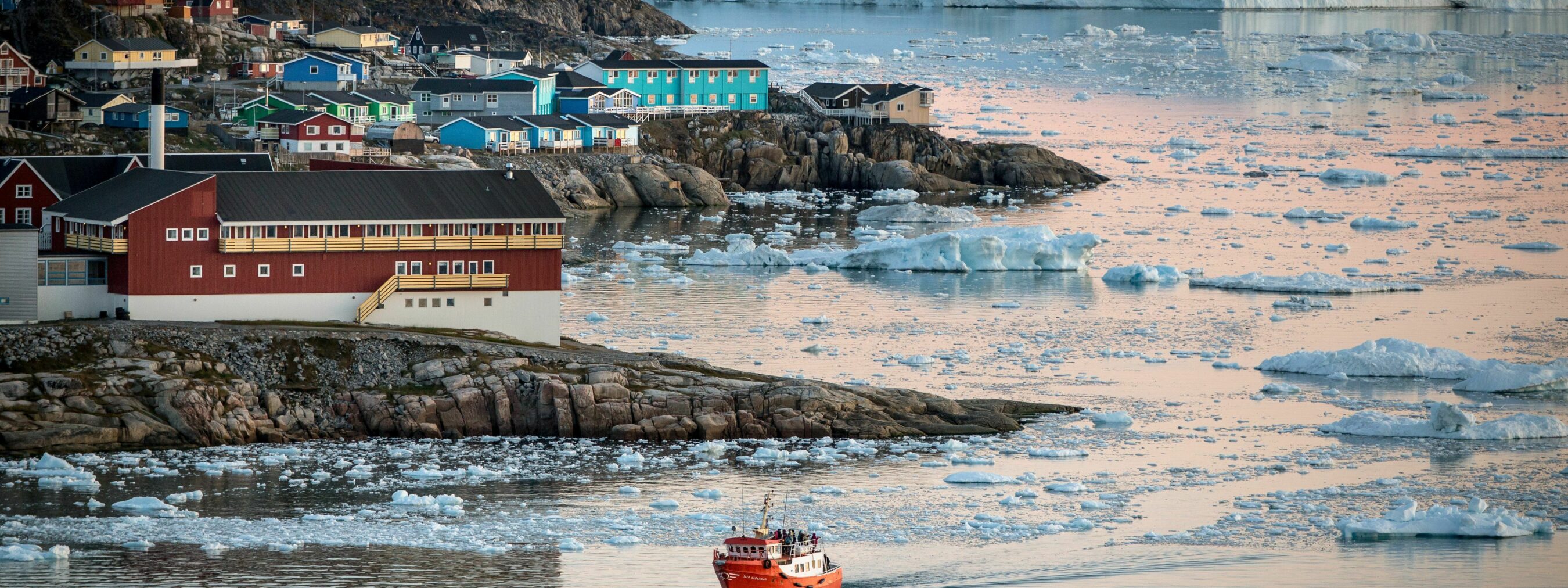 Nordgrönland: Hafen Ilulissat; 
kleines Schiff fährt im Hafen ein, im Hintergrund Eisberge