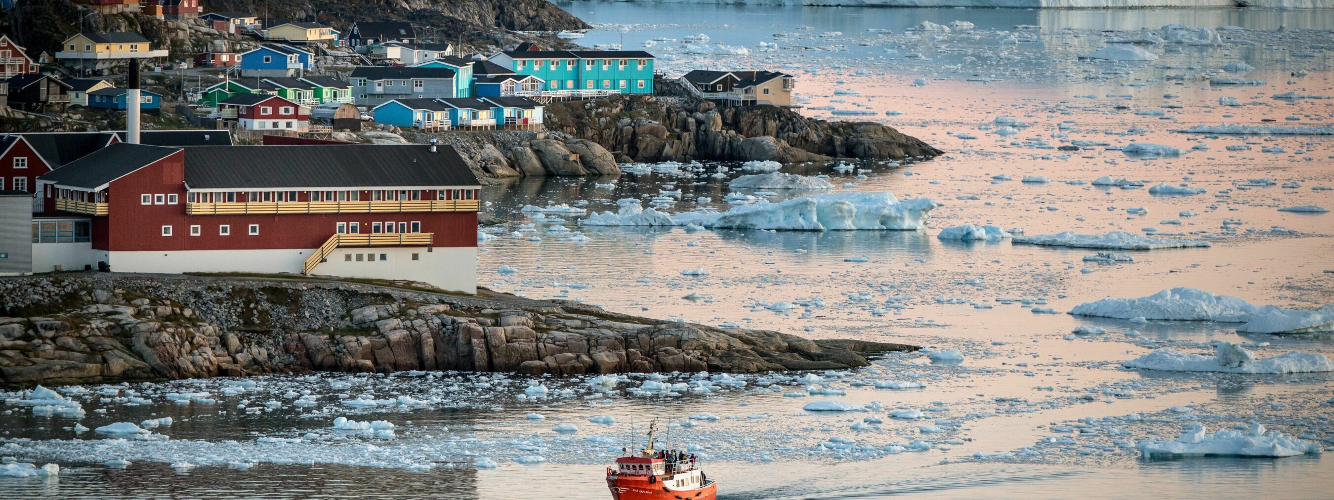 Nordgrönland: Hafen Ilulissat; 
kleines Schiff fährt im Hafen ein, im Hintergrund Eisberge