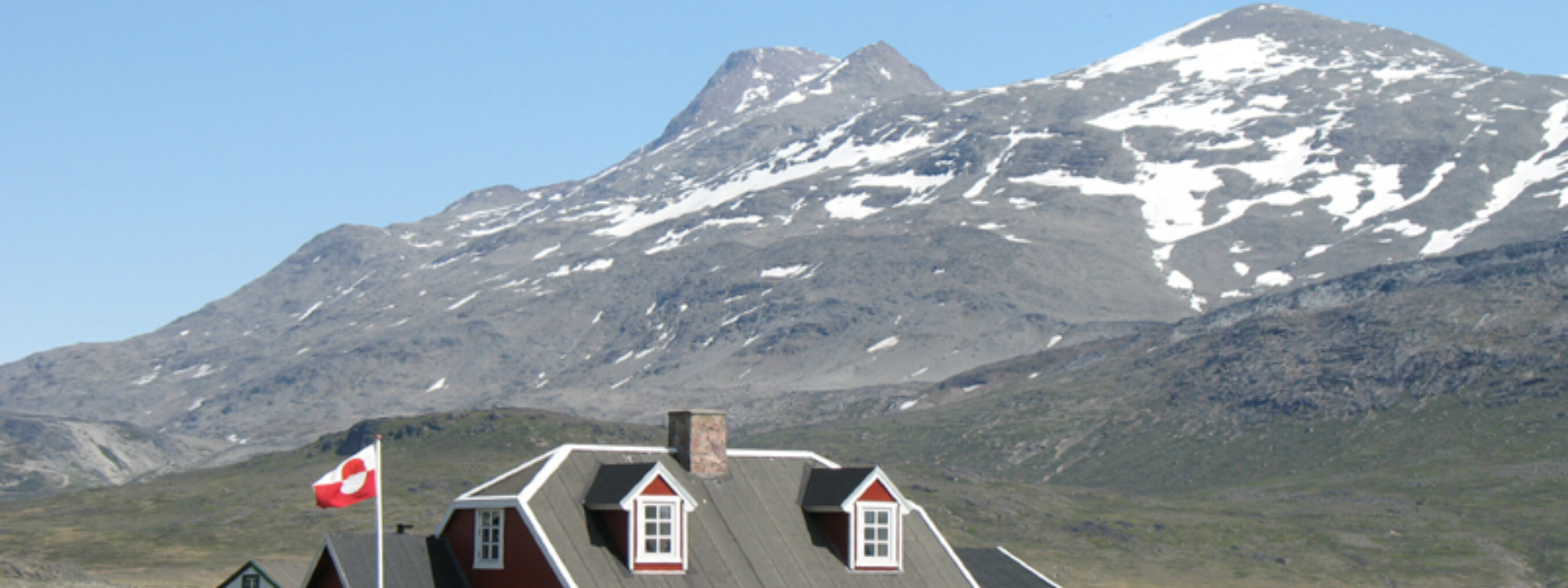 Südgrönland: Siedlung Igaliku
Steinhaus mit Fahne im Garten
Im Hintergrund leicht mit Schnee bedeckte Berge