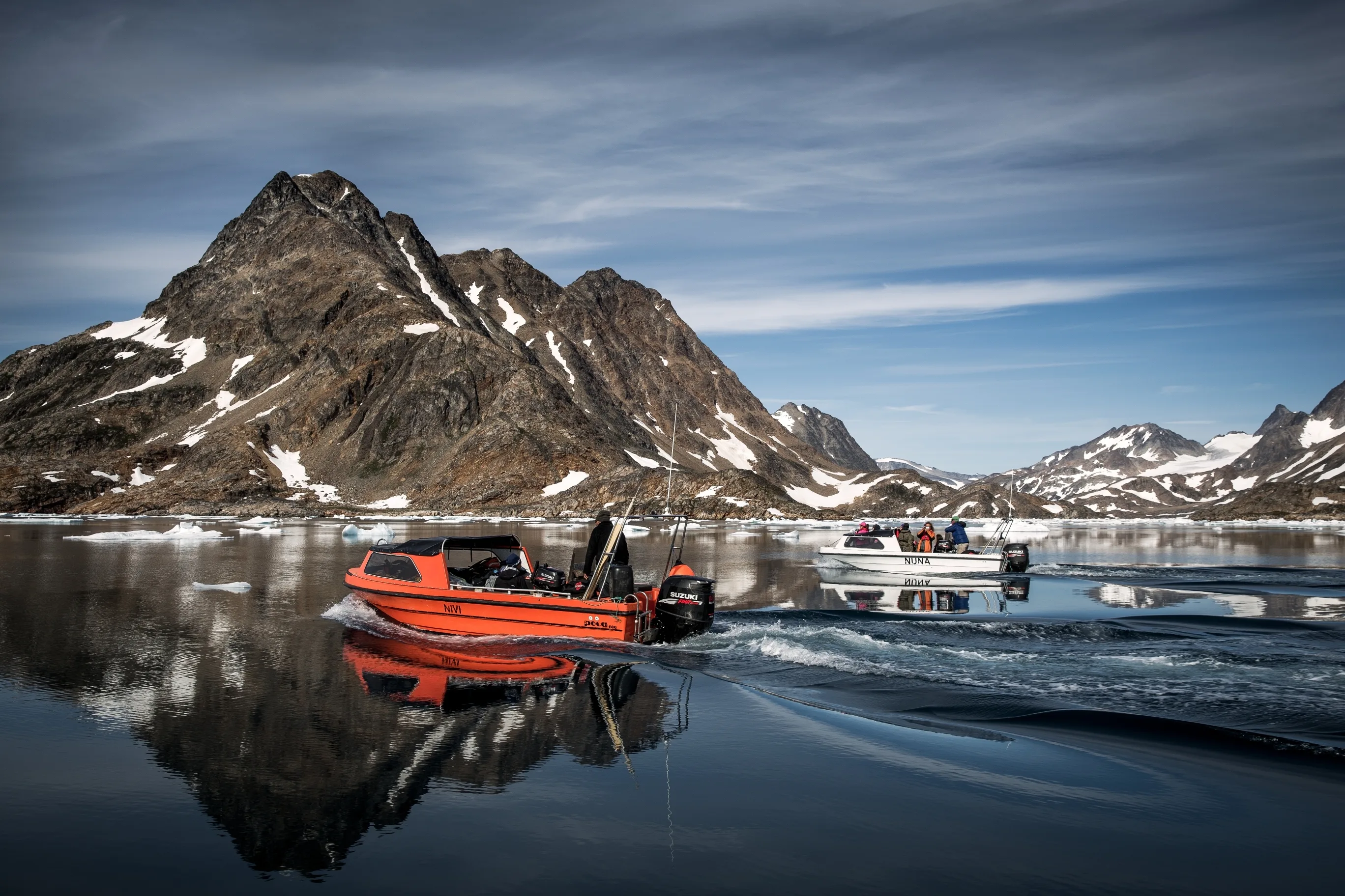 Ostgrönland, zwei Ausflugsboote nahe Kulusuk, im Hintergrund schroffe Berge mit etwas Schnee
