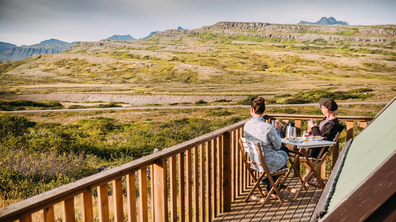 Ein Paar frühstückt auf der Terasse des Ferienhauses mit Blick auf die Berge
