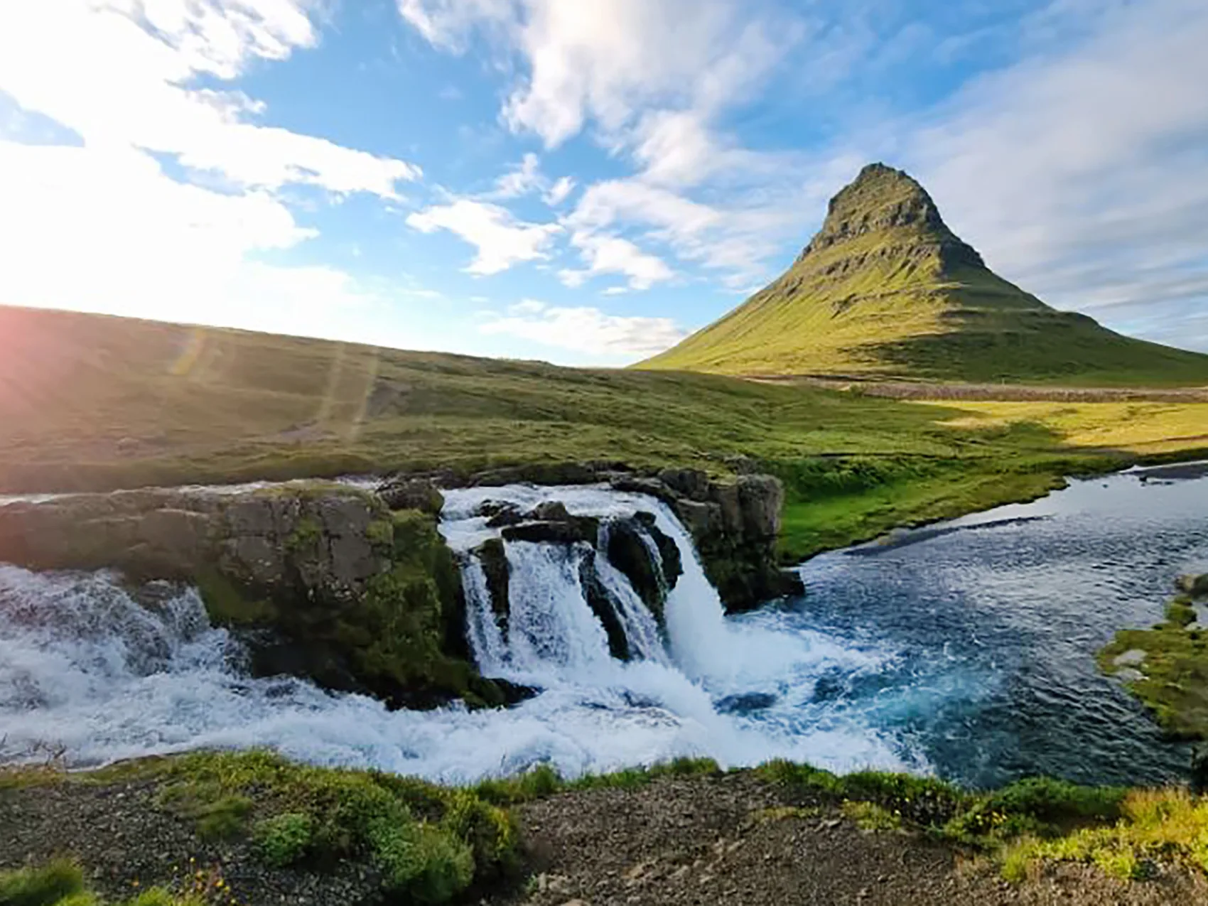 Der Kirkjufell Wasserfall in Island, bei sonnigem und blauem Himmel