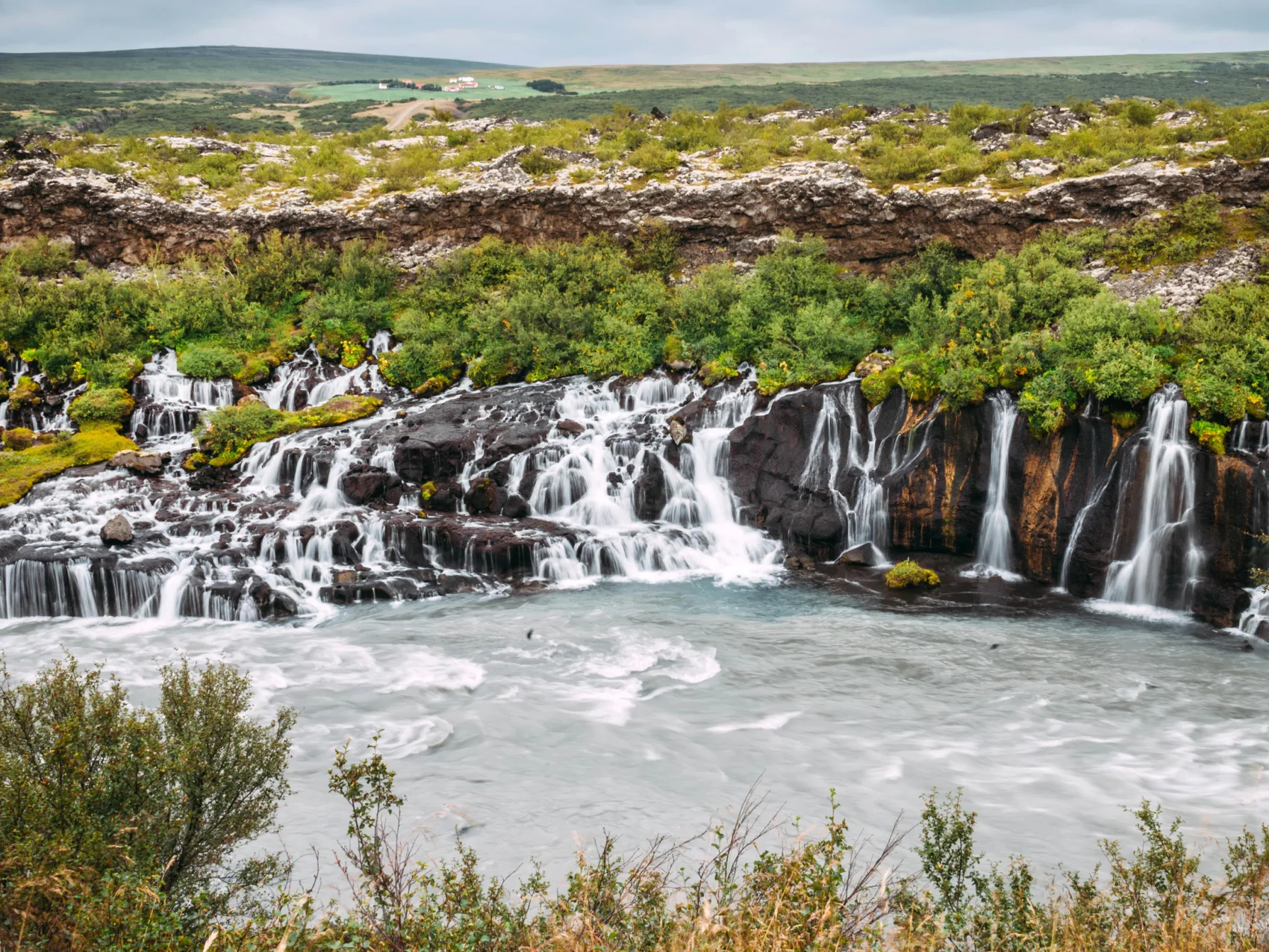 Der Wasserfall Hraunfossar in Island, fließt in einen nebenliegenden Fluss hinein