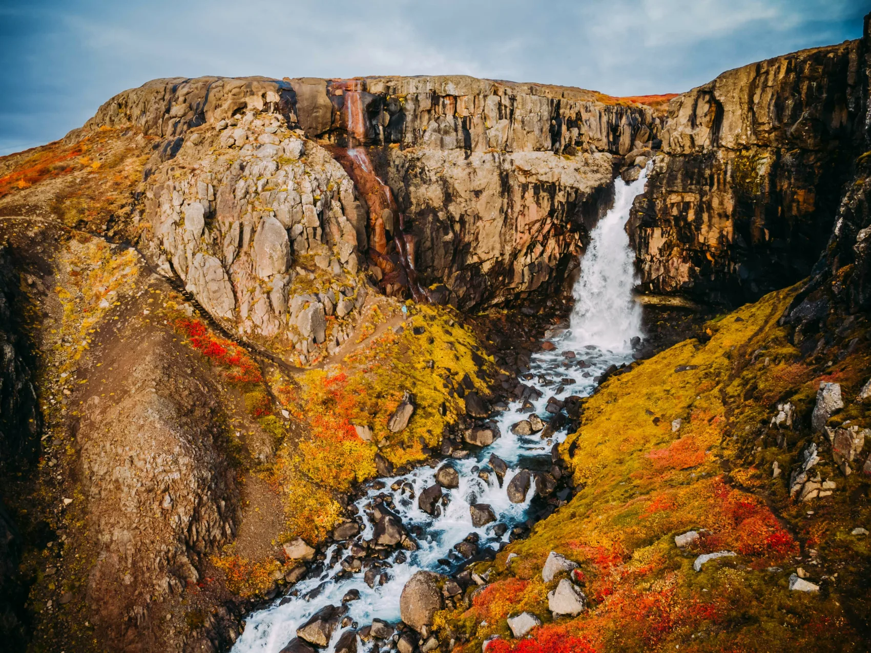 Schöner Wasserfall in felsiger und herbstlicher Landschaft in Island