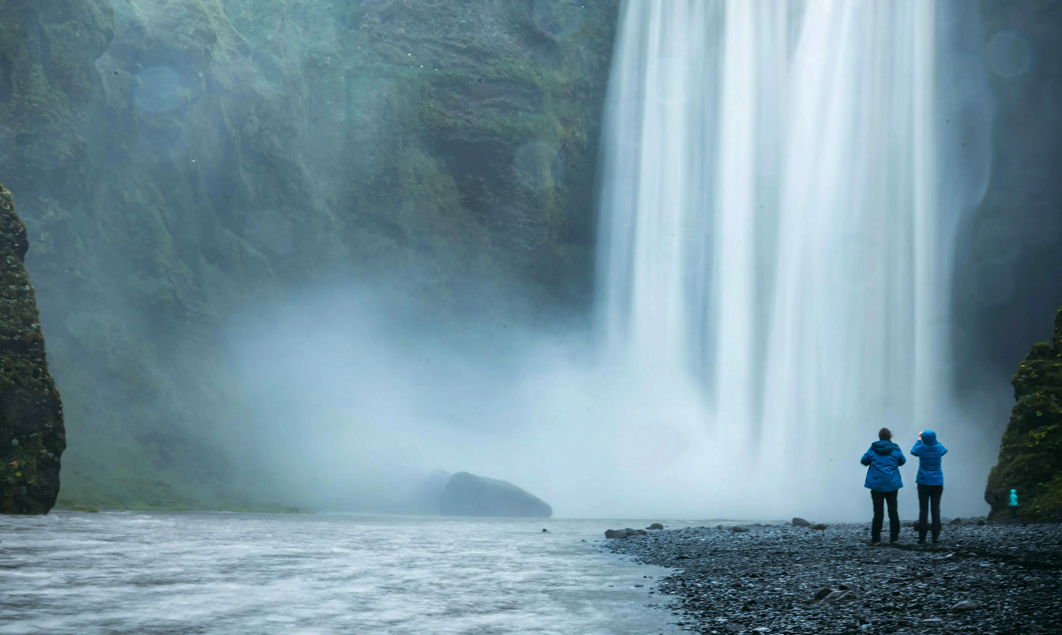 Paar fotografiert in regnerischem Wetter den Skogafoss Wasserfall in Island