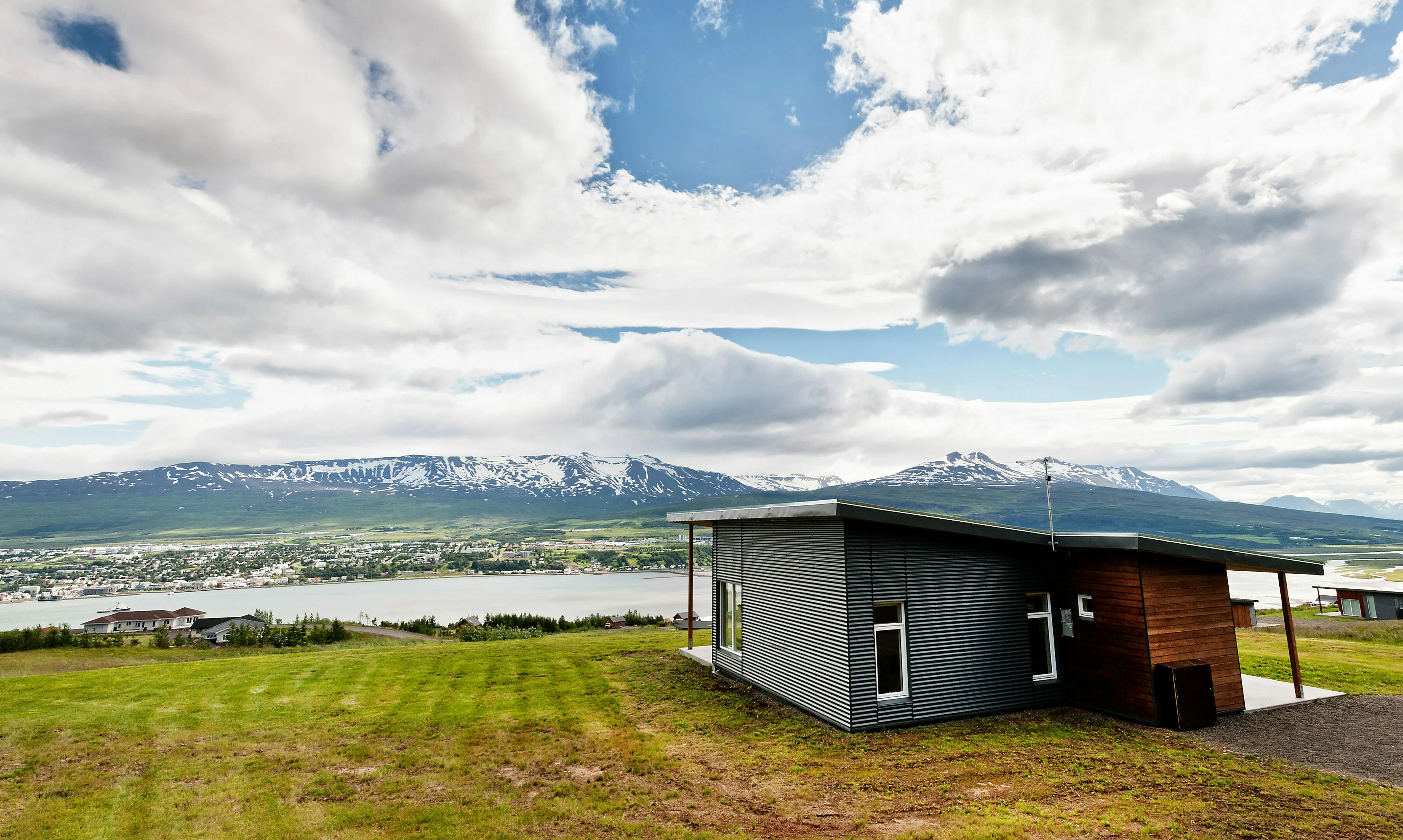 Ein schönes Ferienhaus am Fjord in Akureyri in Island, mit Bergen und vielen Häusern im Hintergrund
