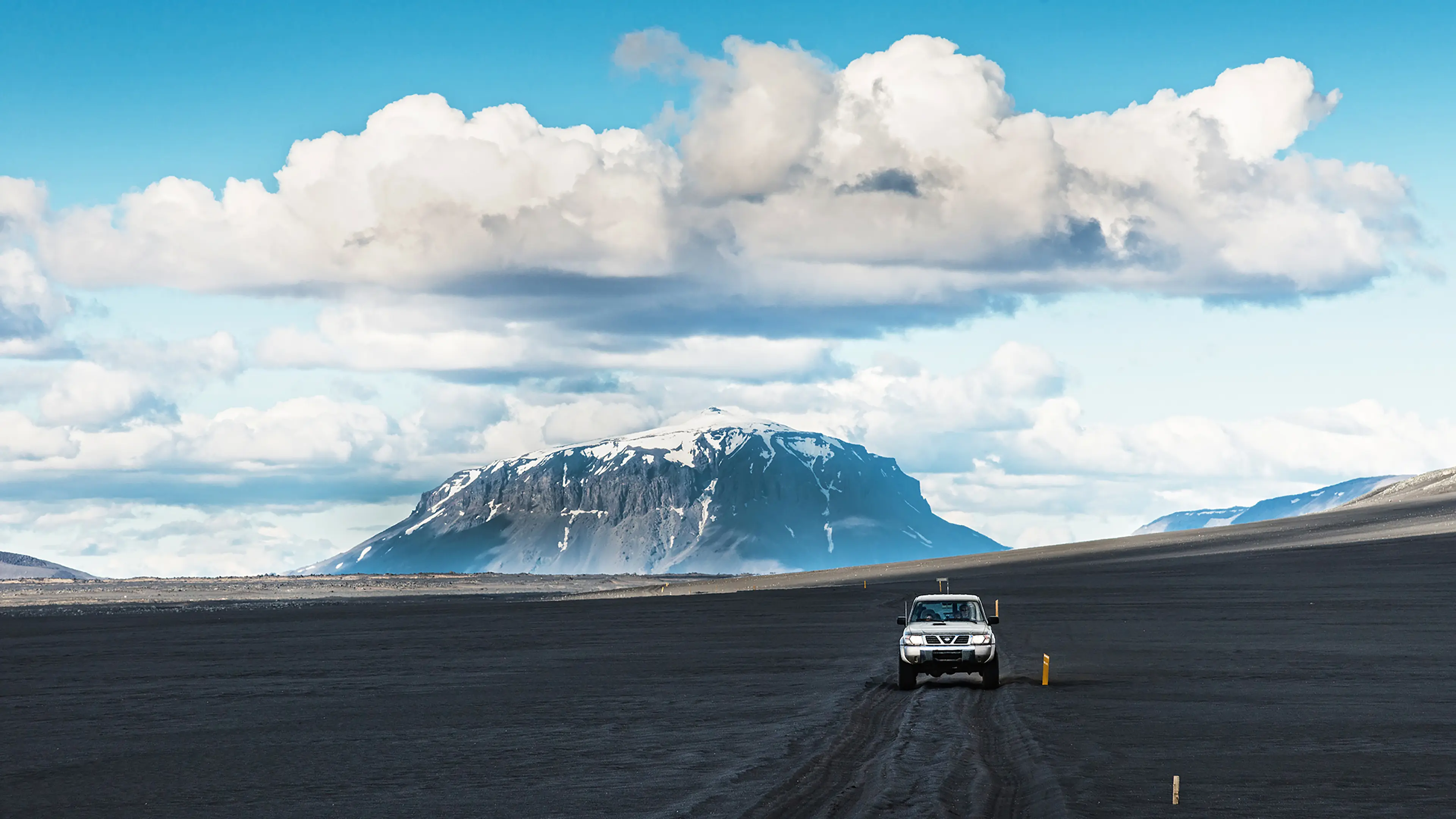 Herdubreid Jeepreise im Hochland Jeep fährt in weiter isländischer Landschaft auf die Kamera zu mit einem Berg im Hintergrund