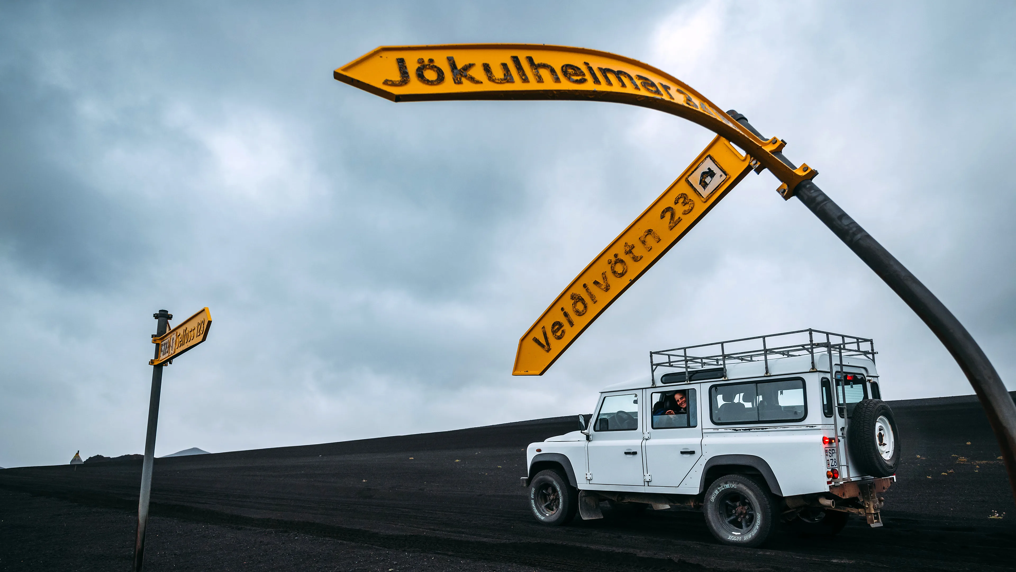 Jeep steht im isländischen Hochland neben einem verbogenen Wegweiser