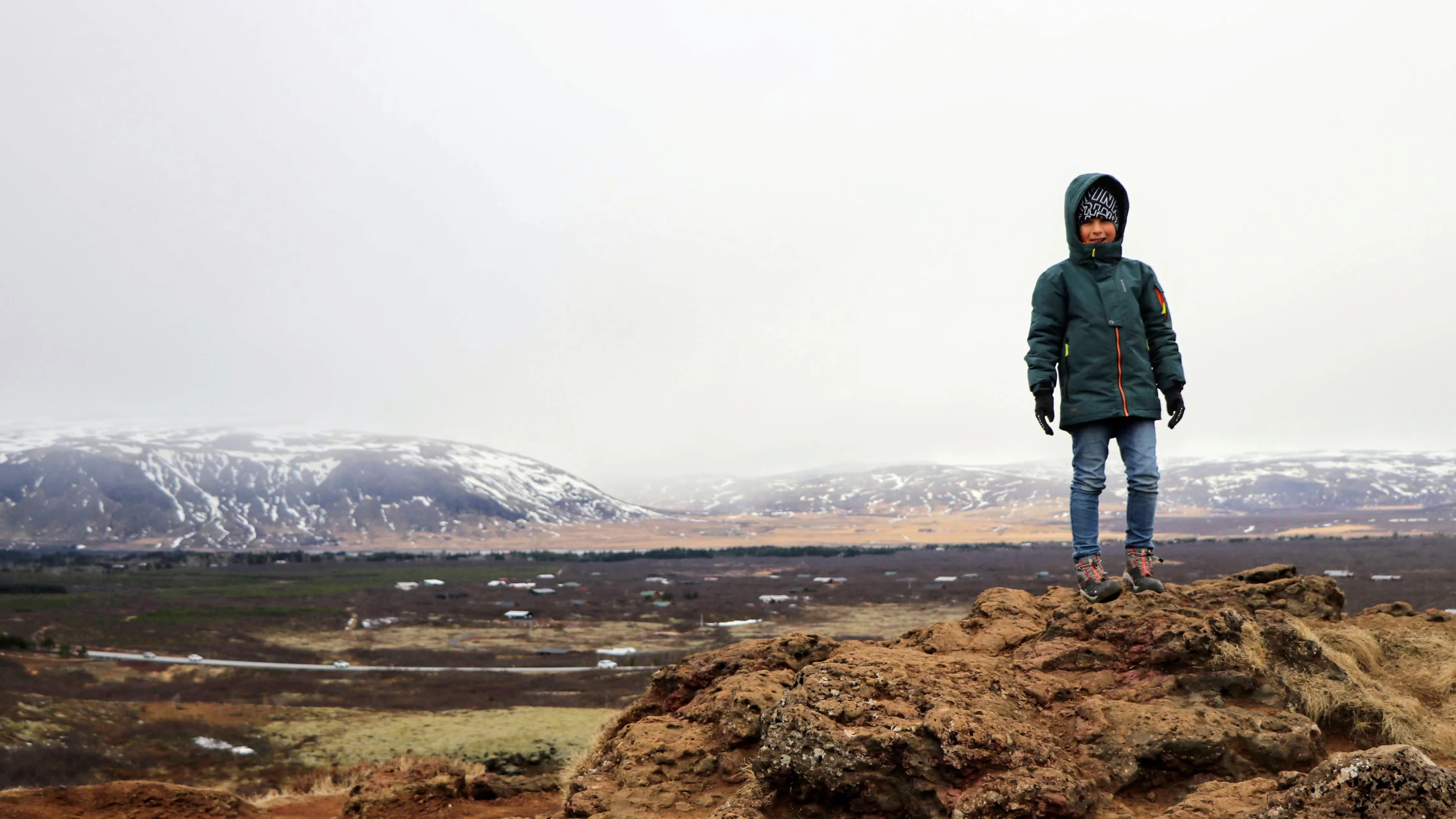 Kind auf einem Felsen in der Winterlandschaft Islands bei nebeligem Wetter