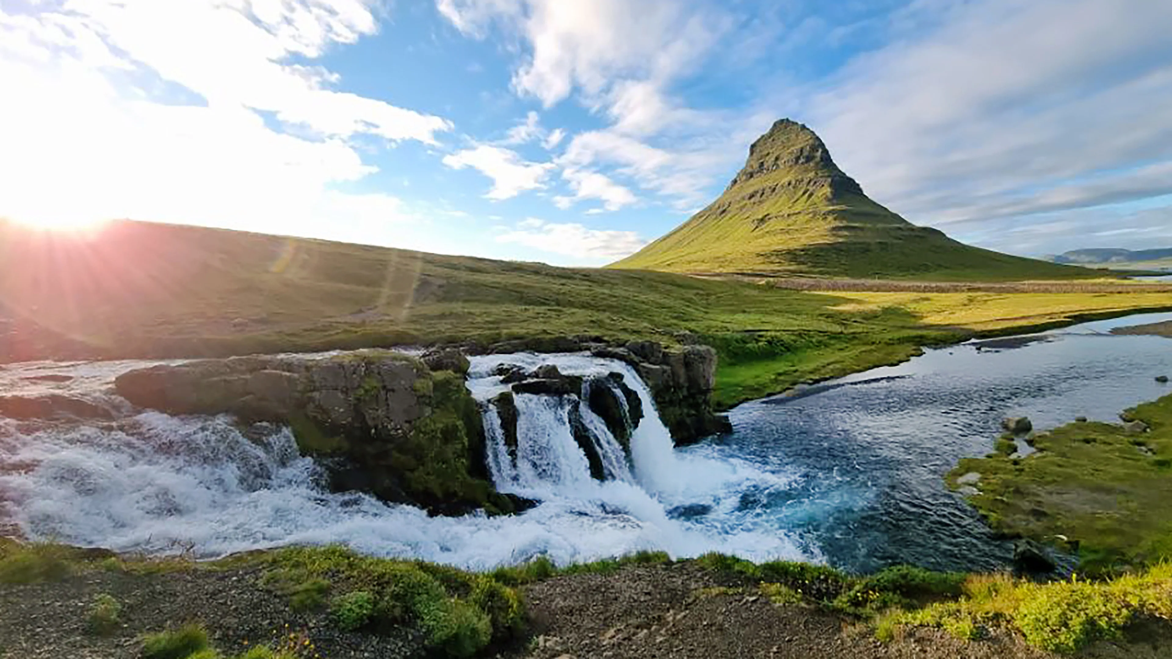 Der Kirkjufell Wasserfall in Island, bei sonnigem und blauem Himmel