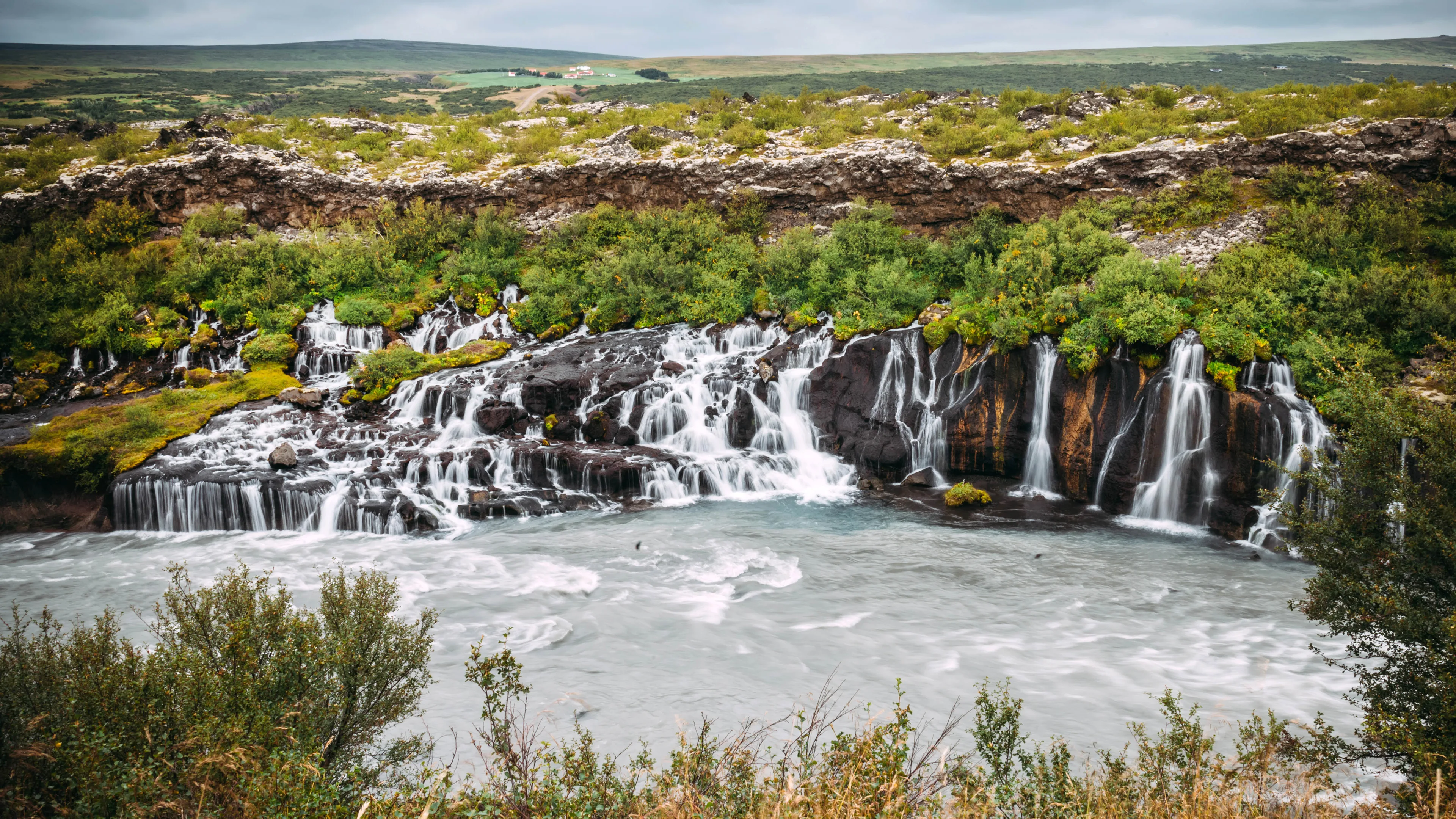 Der Wasserfall Hraunfossar in Island, fließt in einen nebenliegenden Fluss hinein