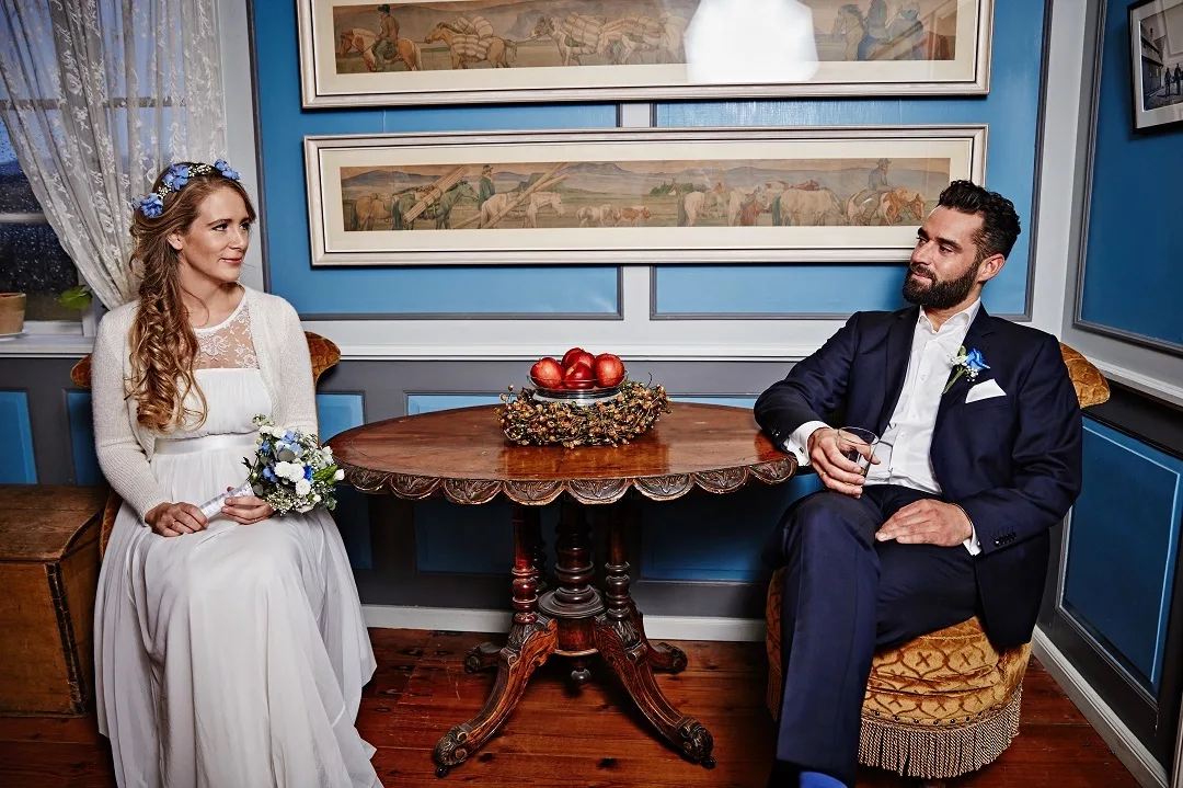 Hochzeitspaar sitzt an altmodischem Tisch im Islandmuseum