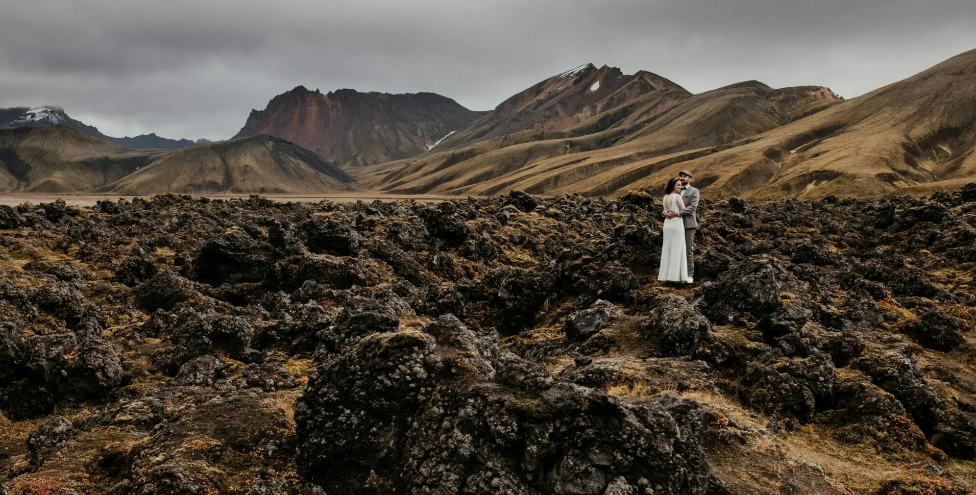 Pärchen im Lavafeld in Island, im Hintergrund Berge
