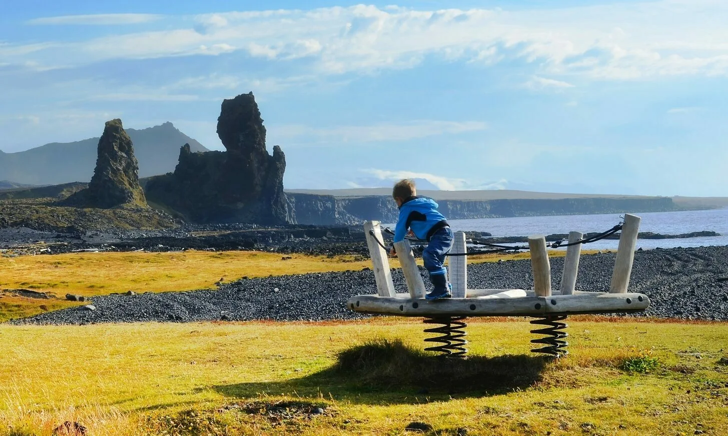 Spielplatz für Kinder in atemberaubender Naturkulisse auf der Snaefellsneshalbinsel, im Hintergrund zwei große Felsen