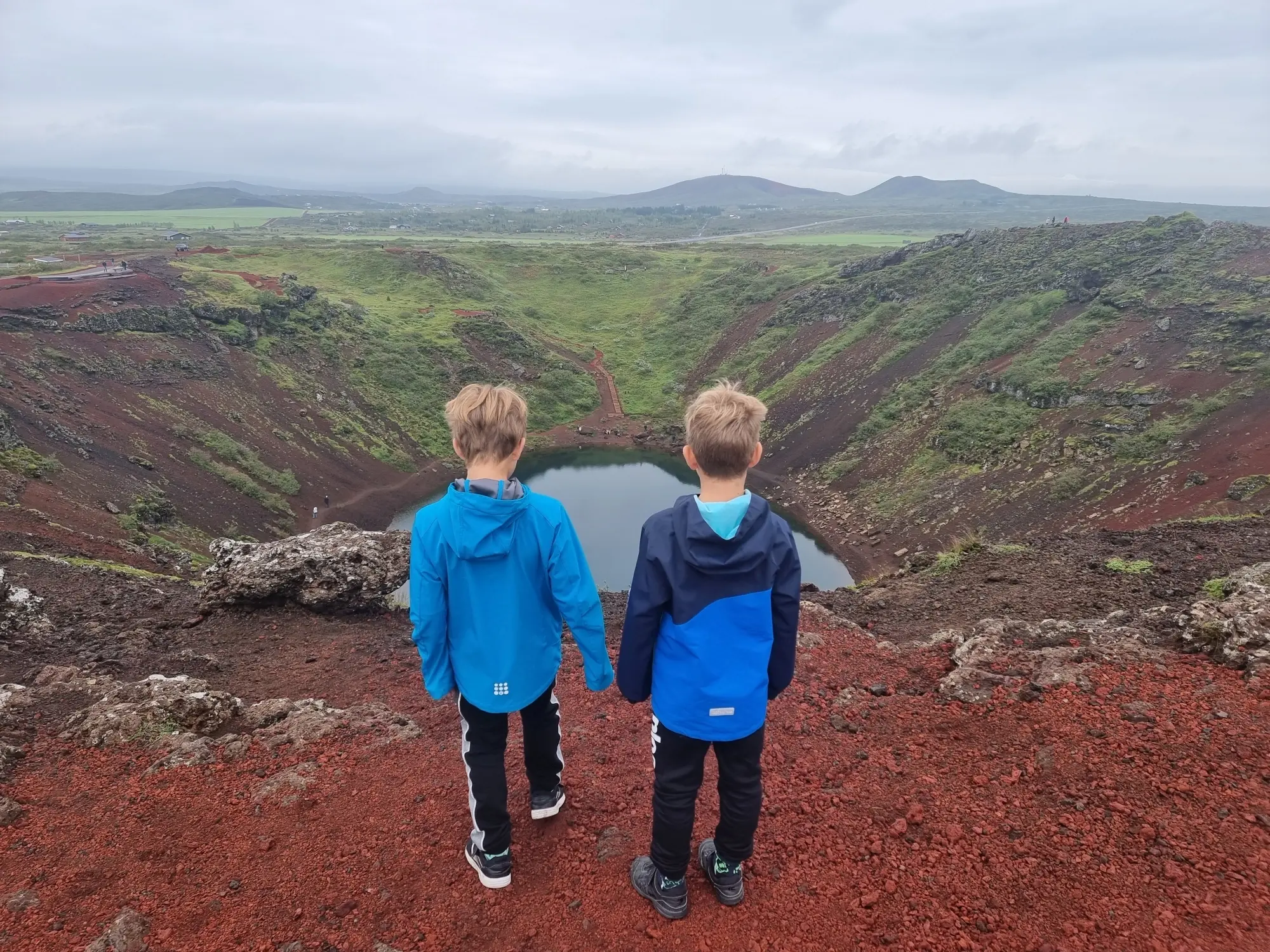 Kinder stehen am Krater Kerið in Island und genießen den Ausblick
