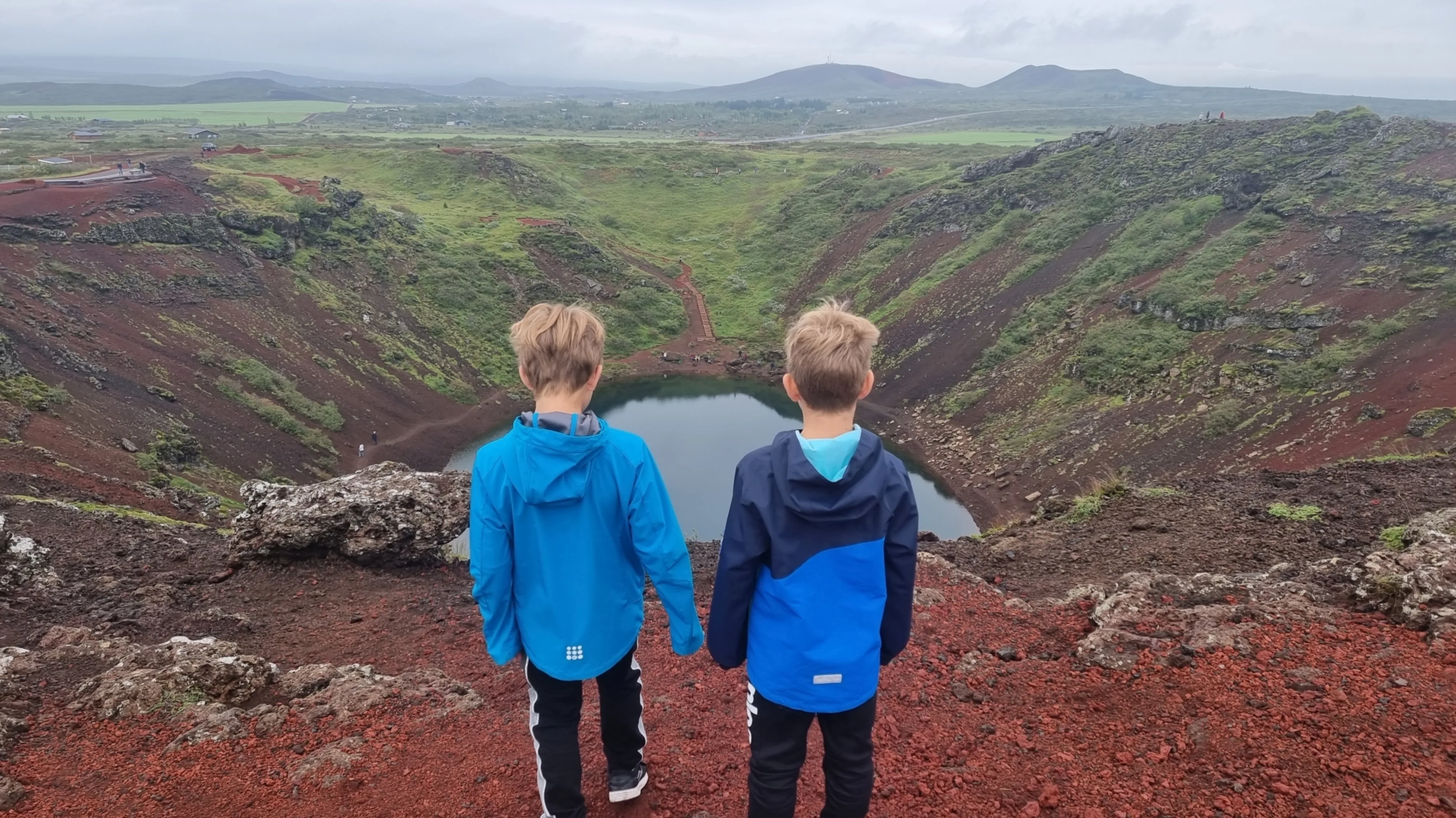 Kinder stehen am Krater Kerið in Island und genießen den Ausblick