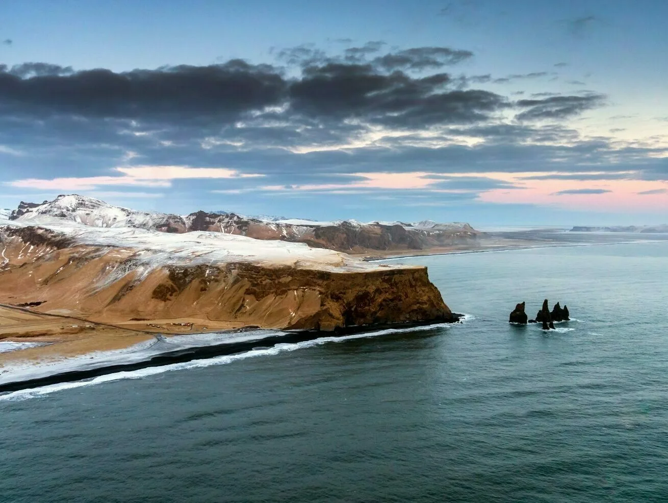 Küste in Südisland mit Schnee bedeckt, schwarzer Sand