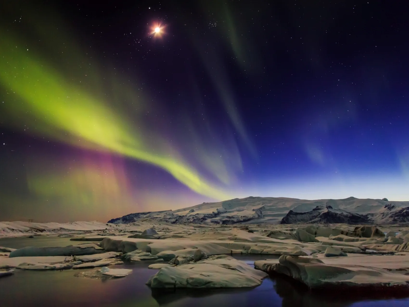 Eine wunderschöne Winternacht am Jökulsárlón, wo die Nordlichter den Himmel bedecken.