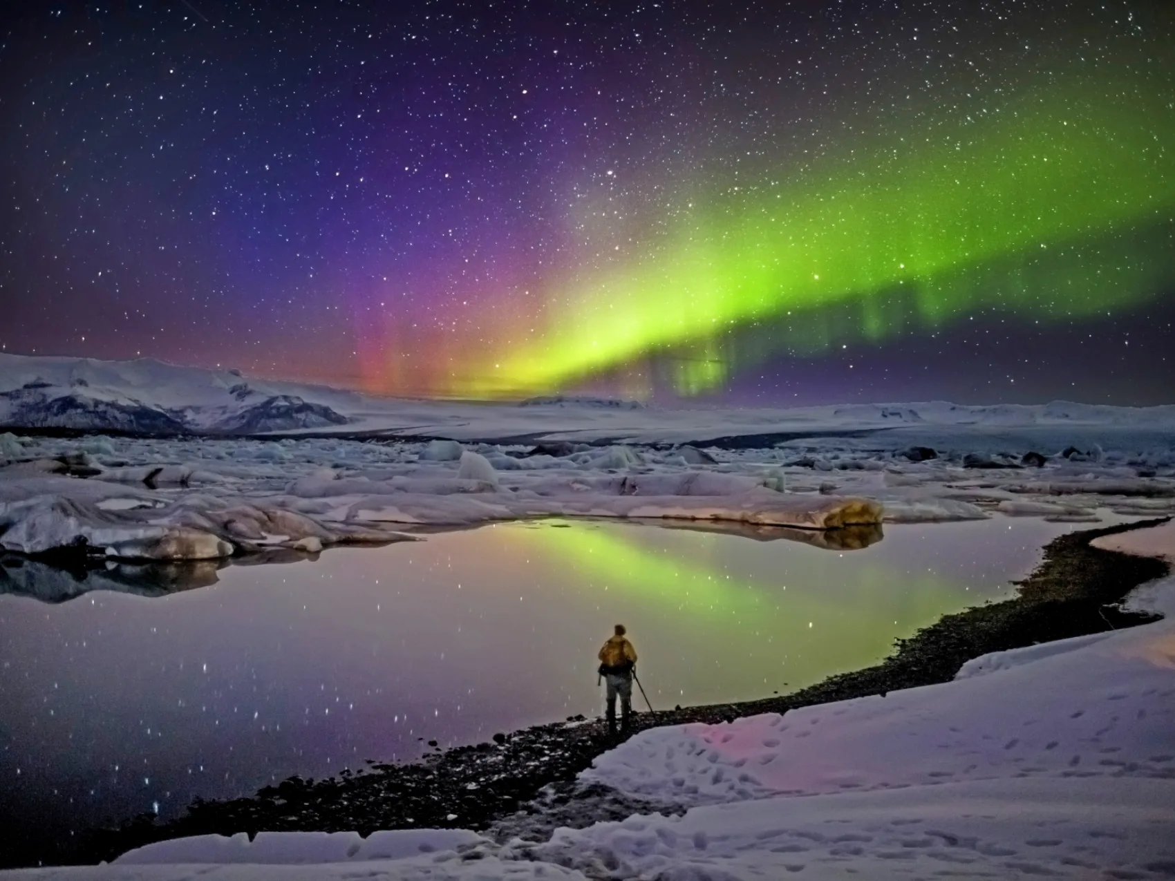 Ein Tourist in Jökulsárlón genießt es, die Nordlichter zu beobachten.