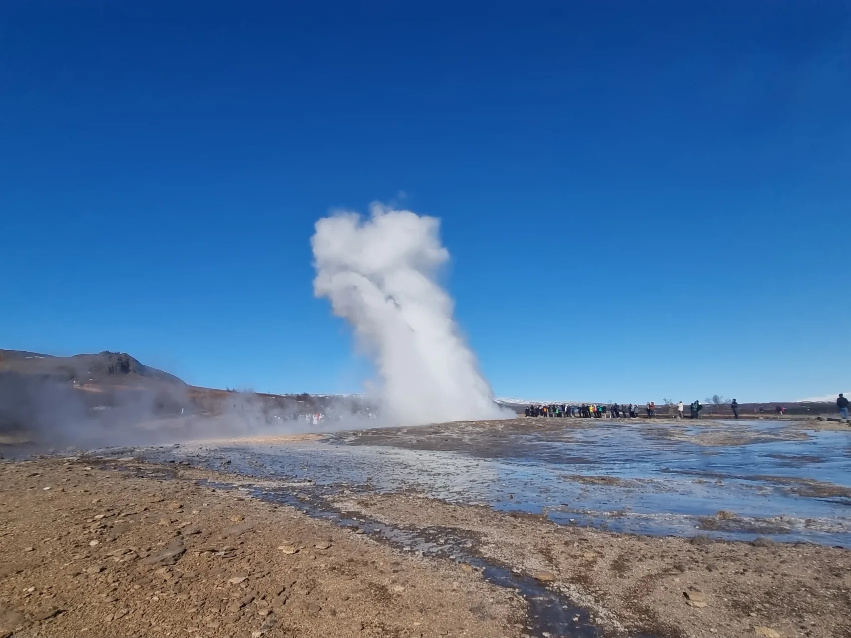 Geysir heiße Quelle, umgeben von Touristen auf einem schönen Wintertag.