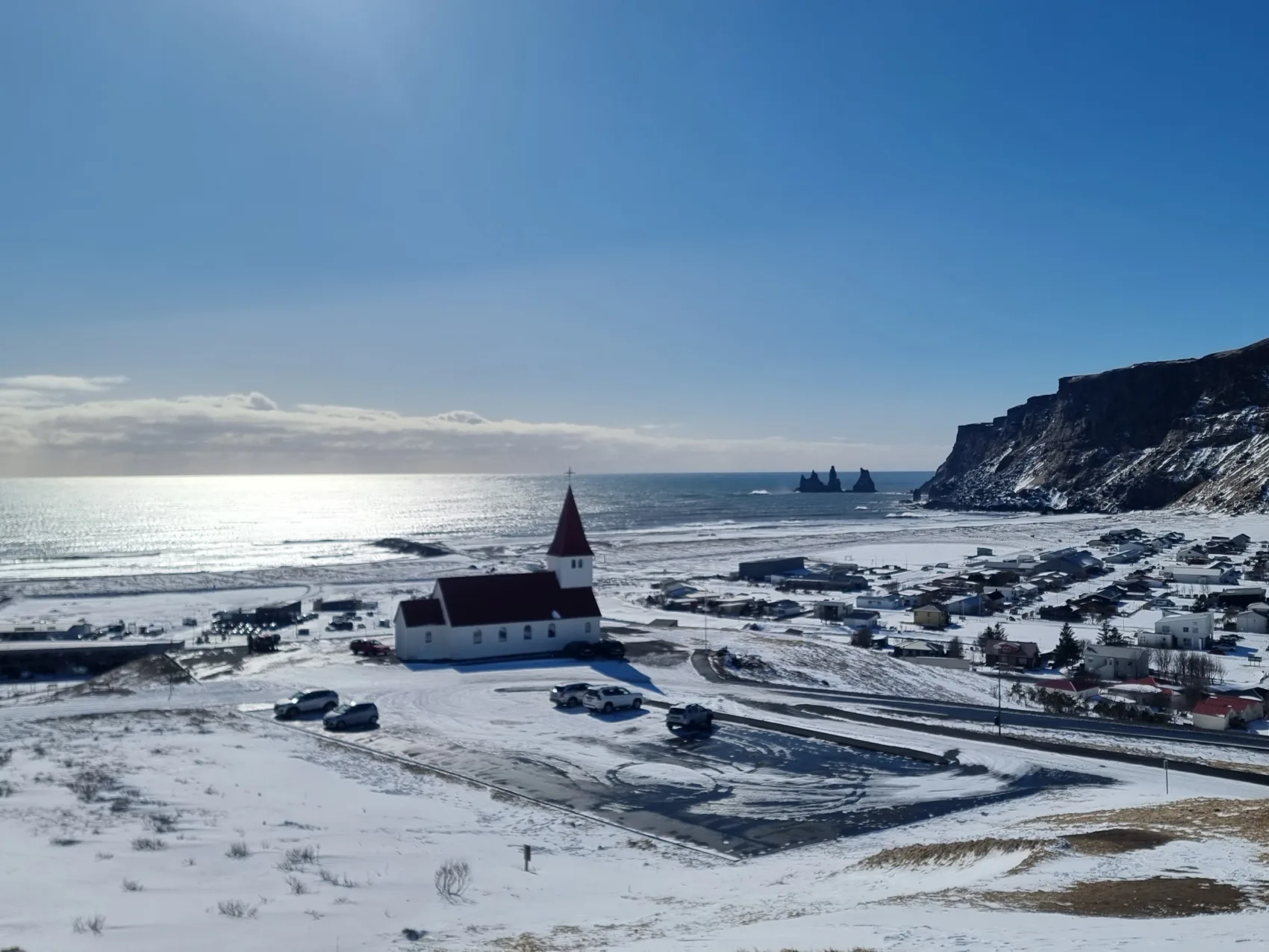 Blick auf den Vík í Mýrdal an einem schönen Wintertag, an dem alles mit Schnee bedeckt ist.
