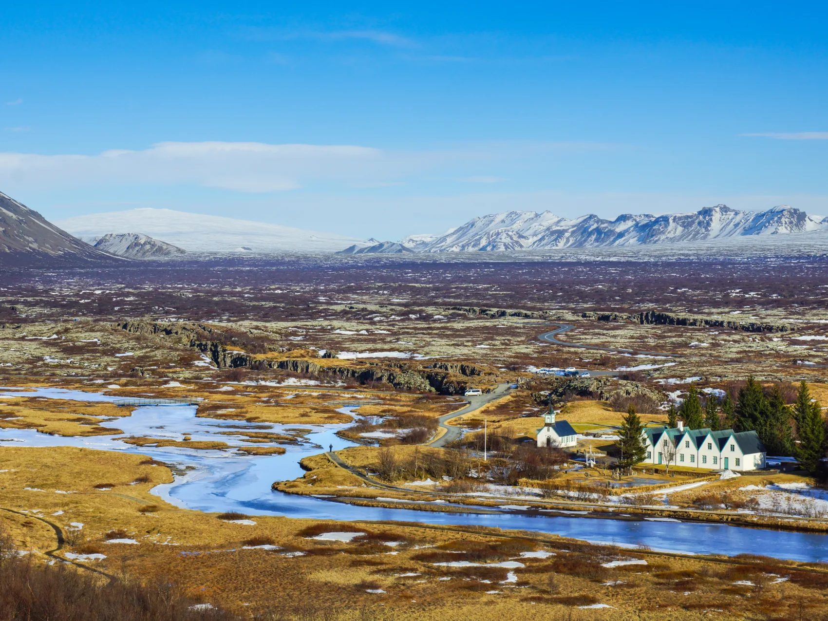 Blick auf den Þingvellir-Nationalpark in Südisland, wo ein Bach durch Moos und Felsen fließt und im Hintergrund Berge zu sehen sind