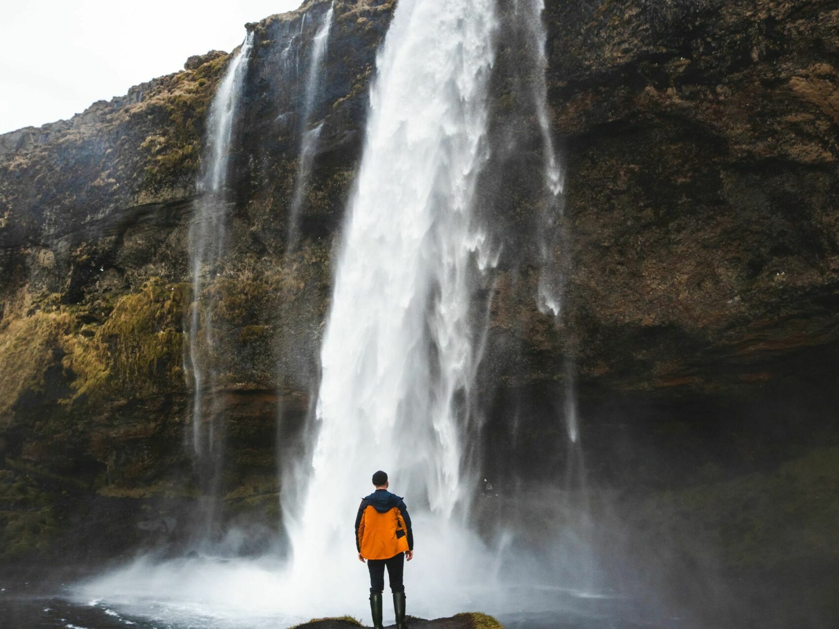 Seljalandsfoss Wasserfall (Südisland) im Winter, Person steht im Vordergrund mit Blick auf Wasserfall, Foto: Business Iceland