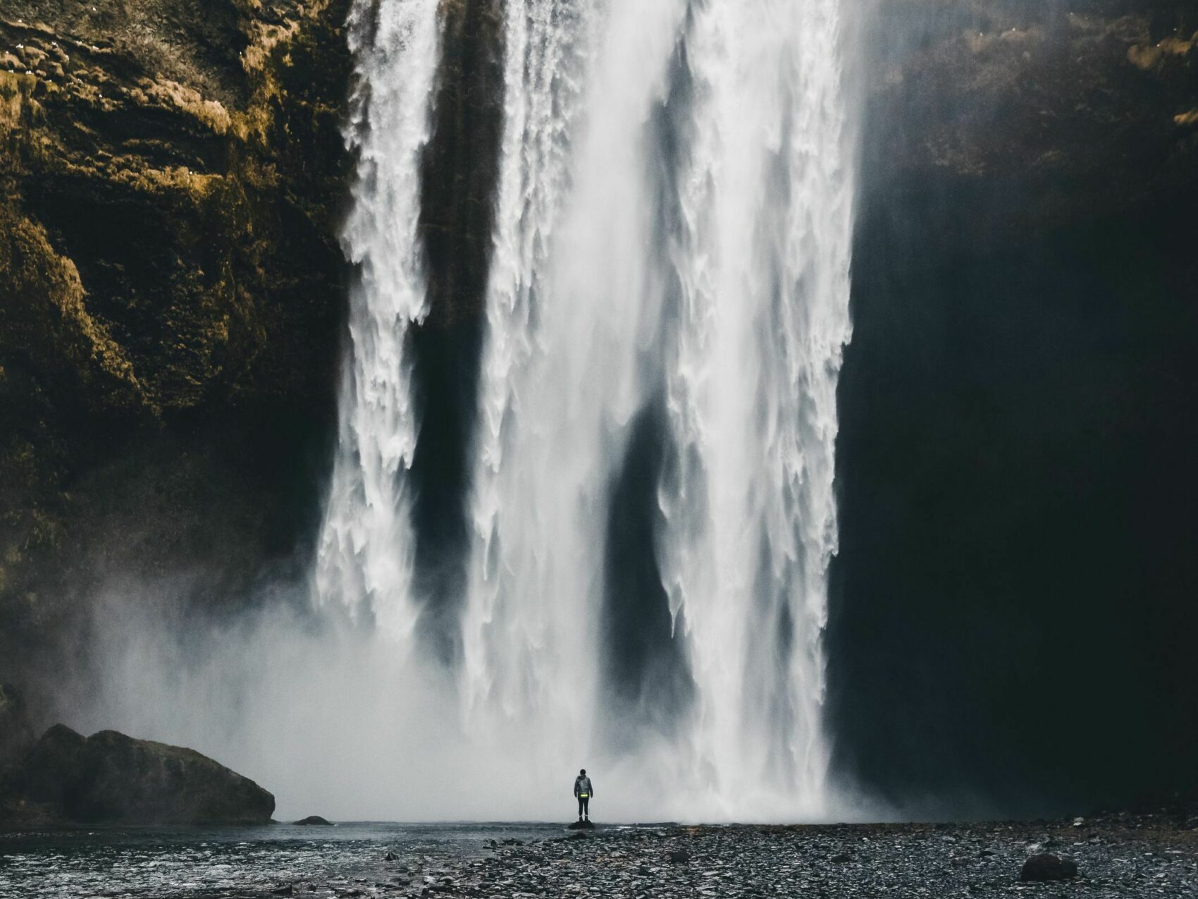 Skogafoss Wasserfall in Südisland, einzelne Person steht vor dem großen Wasserfall