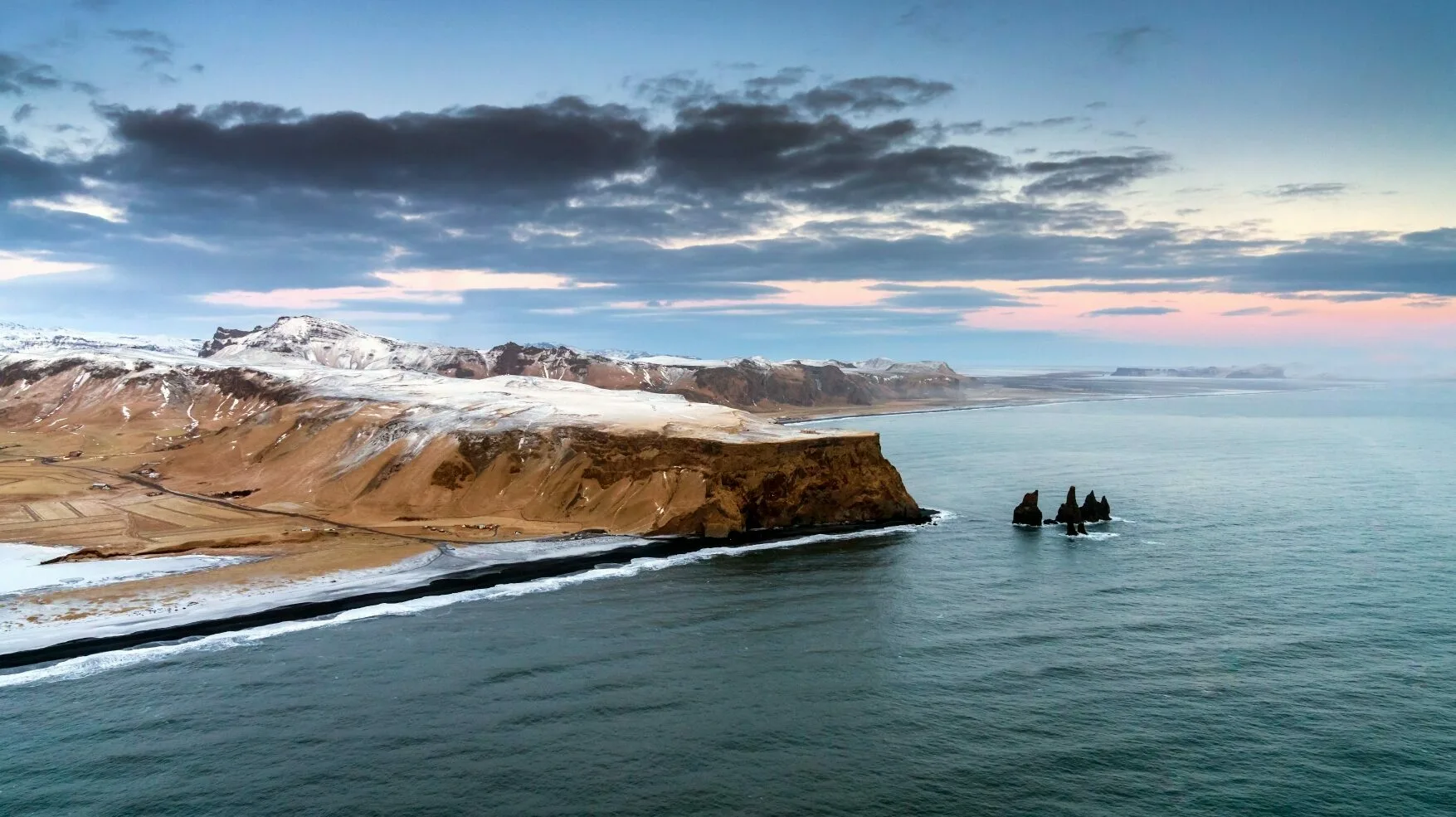 Küste in Südisland mit Schnee bedeckt, schwarzer Sand