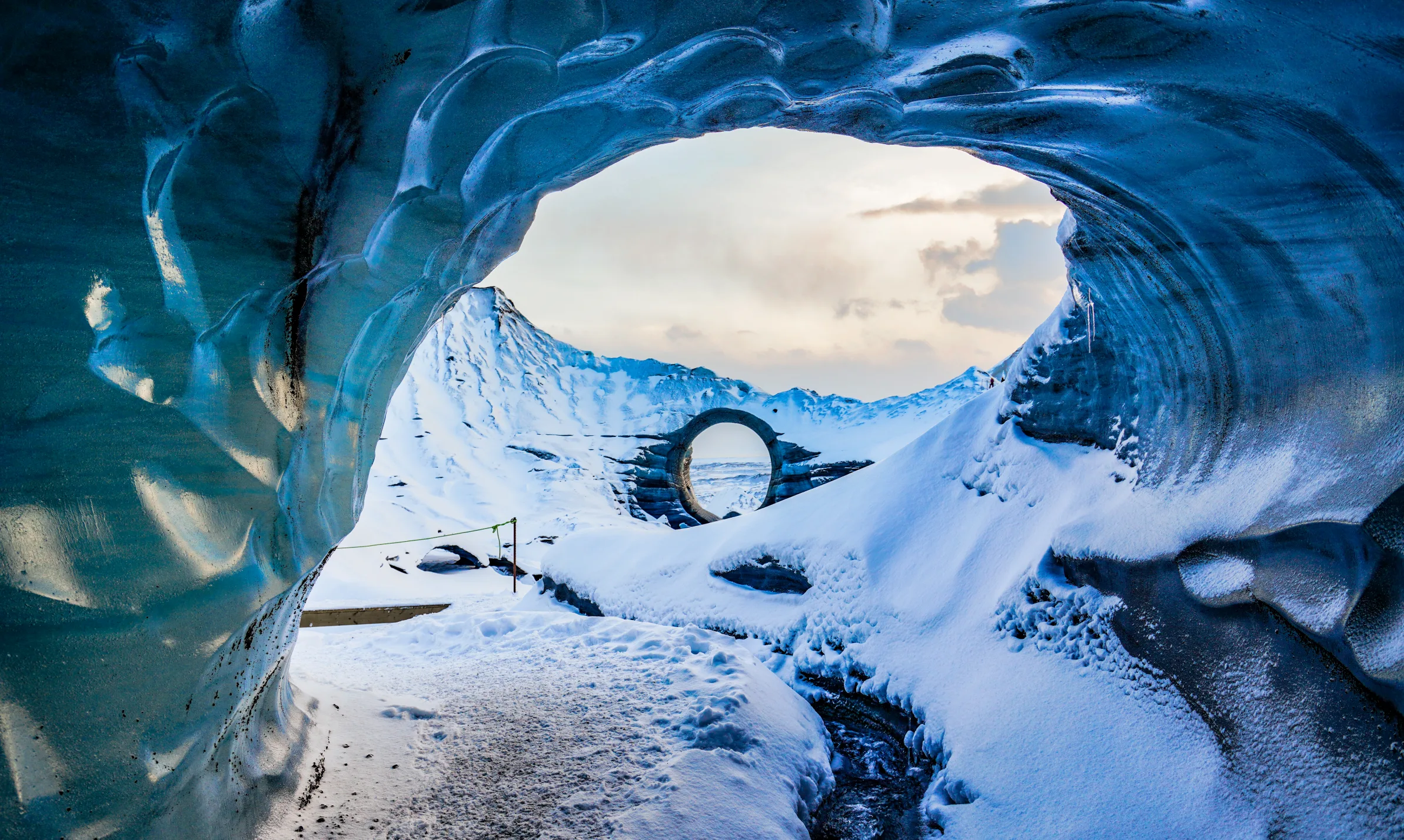 Blick aus einer Eishöhle über einen verschneiten Wanderweg.