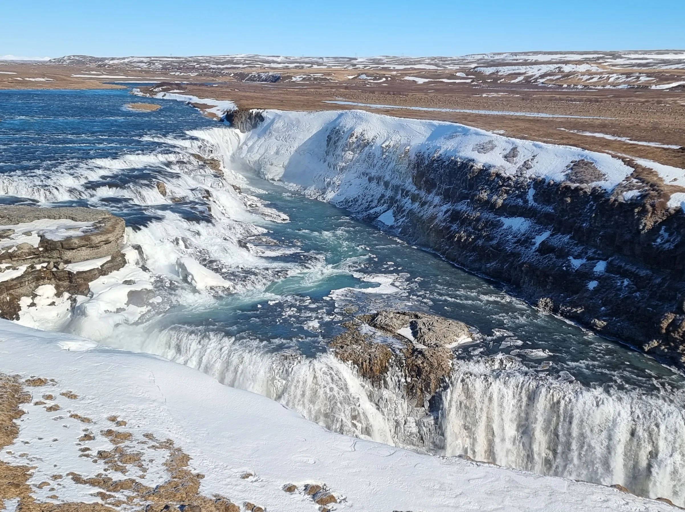 Der Wasserfall Goðafoss in Südisland mit einer verschneiten Landschaft drumherum.