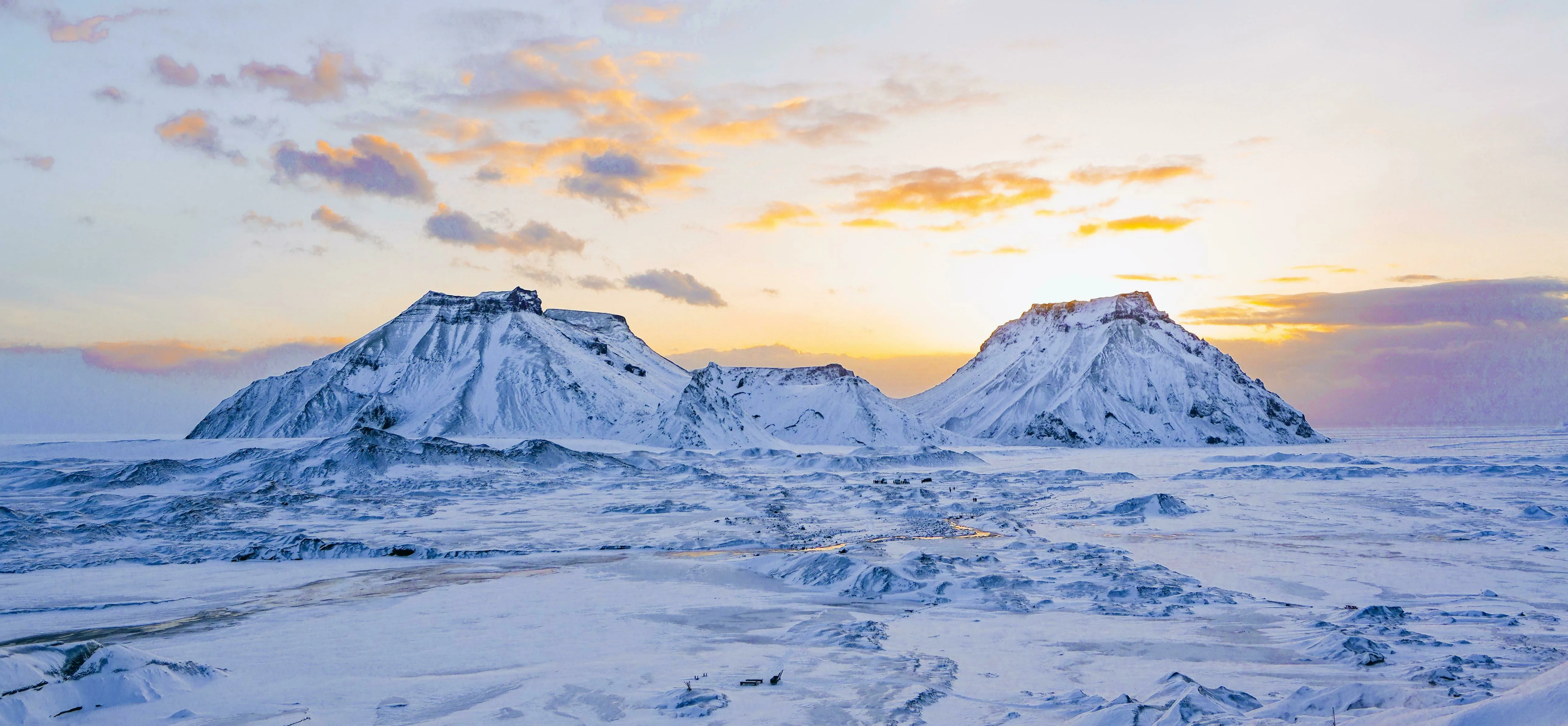 Eine Winterlandschaft mit schneebedeckten Bergen bei einem wunderschönen Sonnenaufgang.