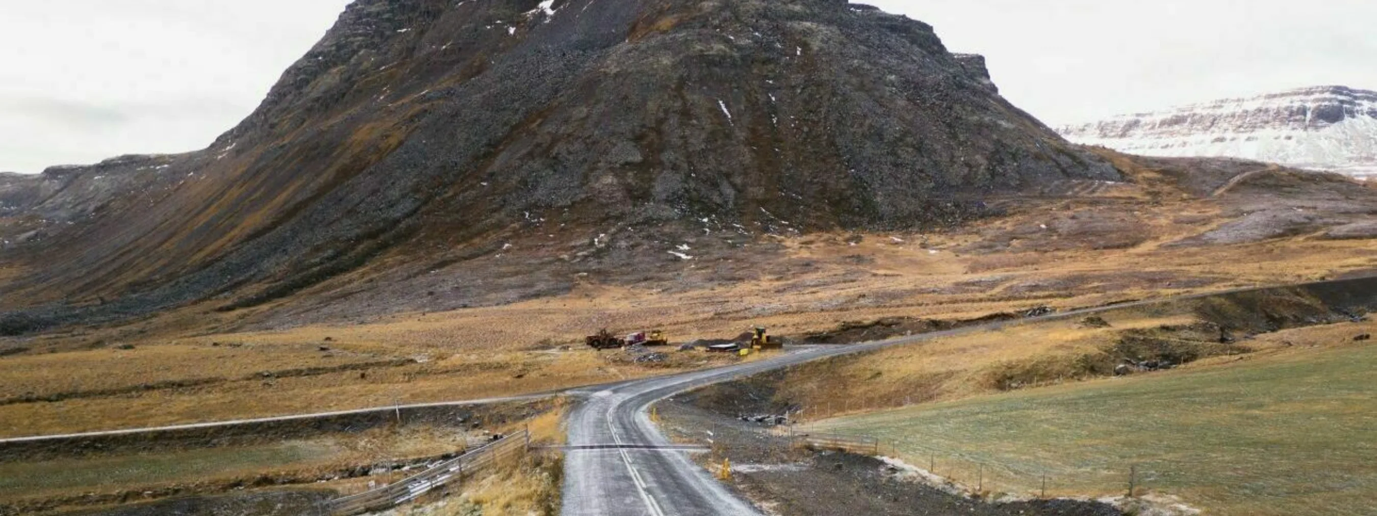 Ein Auto fährt auf einer Straße vor dramatischer Bergkulisse im Hintergrund