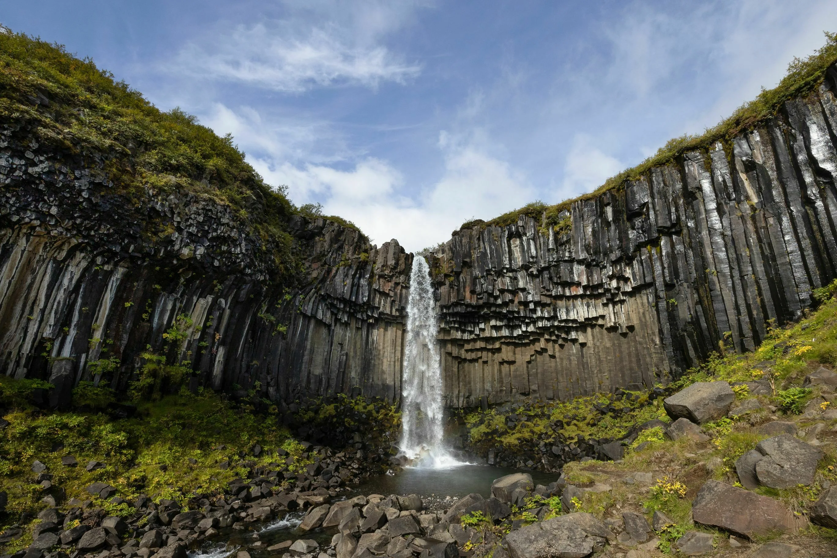 Island Wasserfall Svartifoss, Foto: Timo Klingebiel
Zwischen Basaltsäulen stürzt das Wasserfall des Svartifoss in die Tiefe
Der Himmel ist blau mit leichten Wolken.