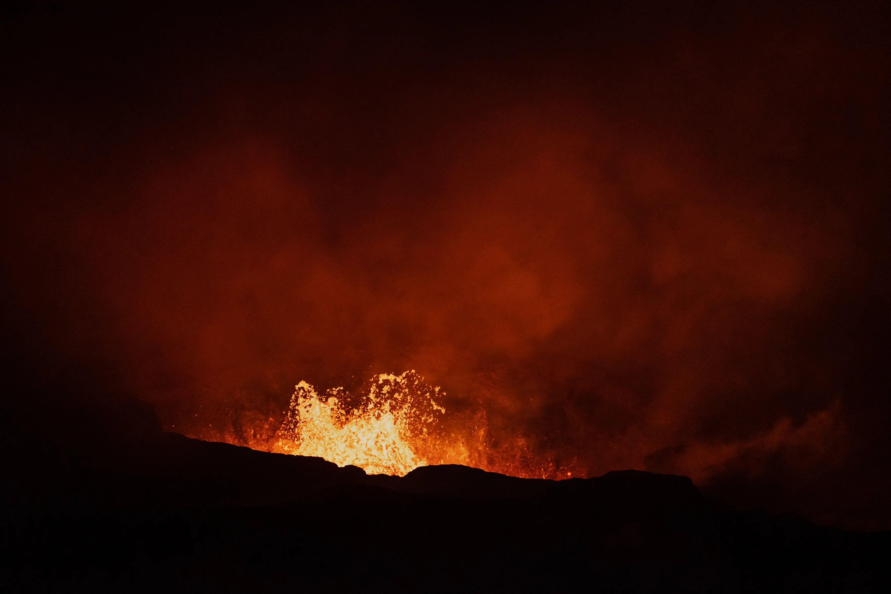 Nachtansicht eines Vulkanes in Island, der gerade Lava spuckt.