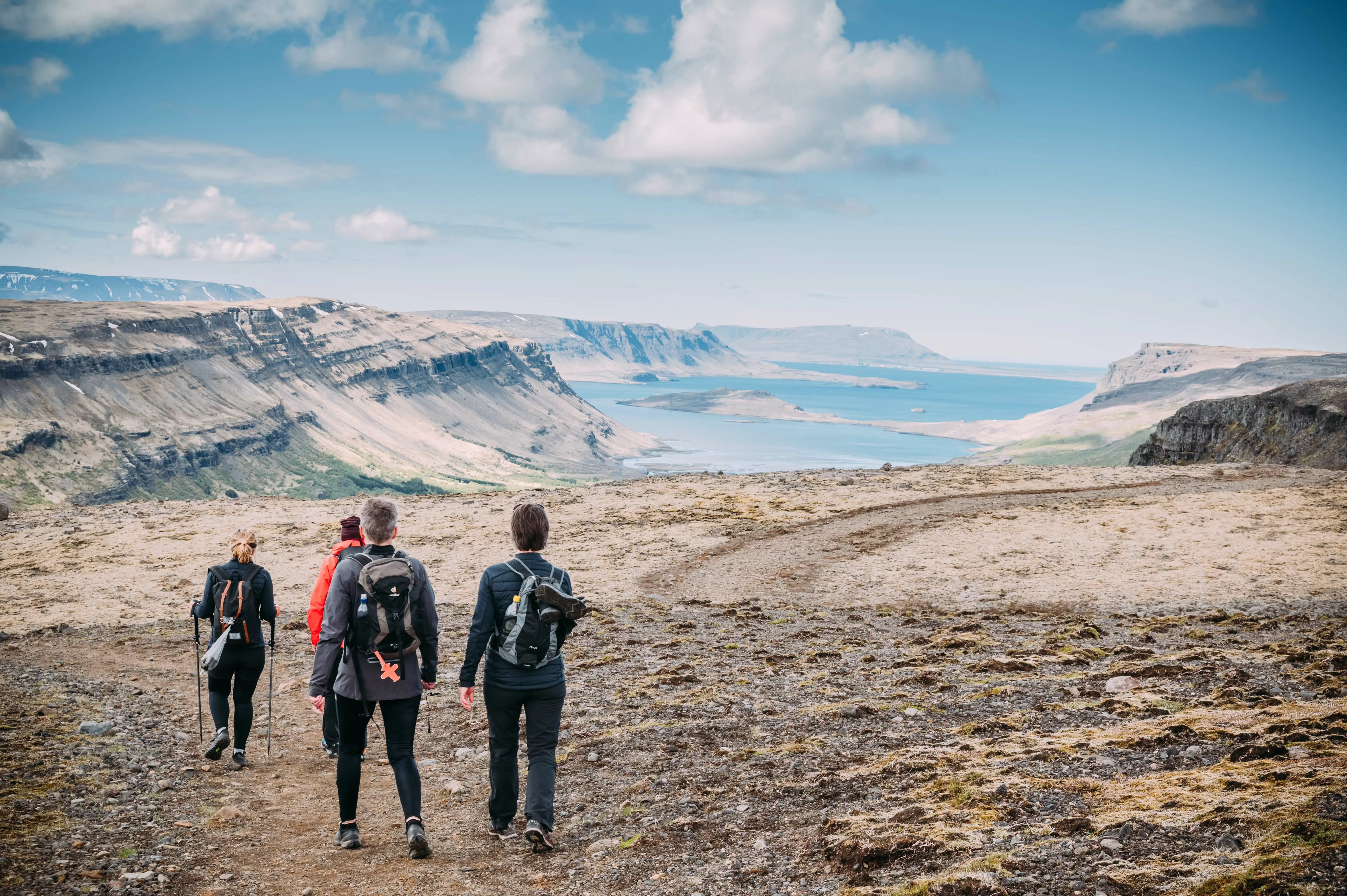 4 Wanderer wandern in szenischer Landschaft auf einem Berg mit Ausblick auf das Meer und weitere berge